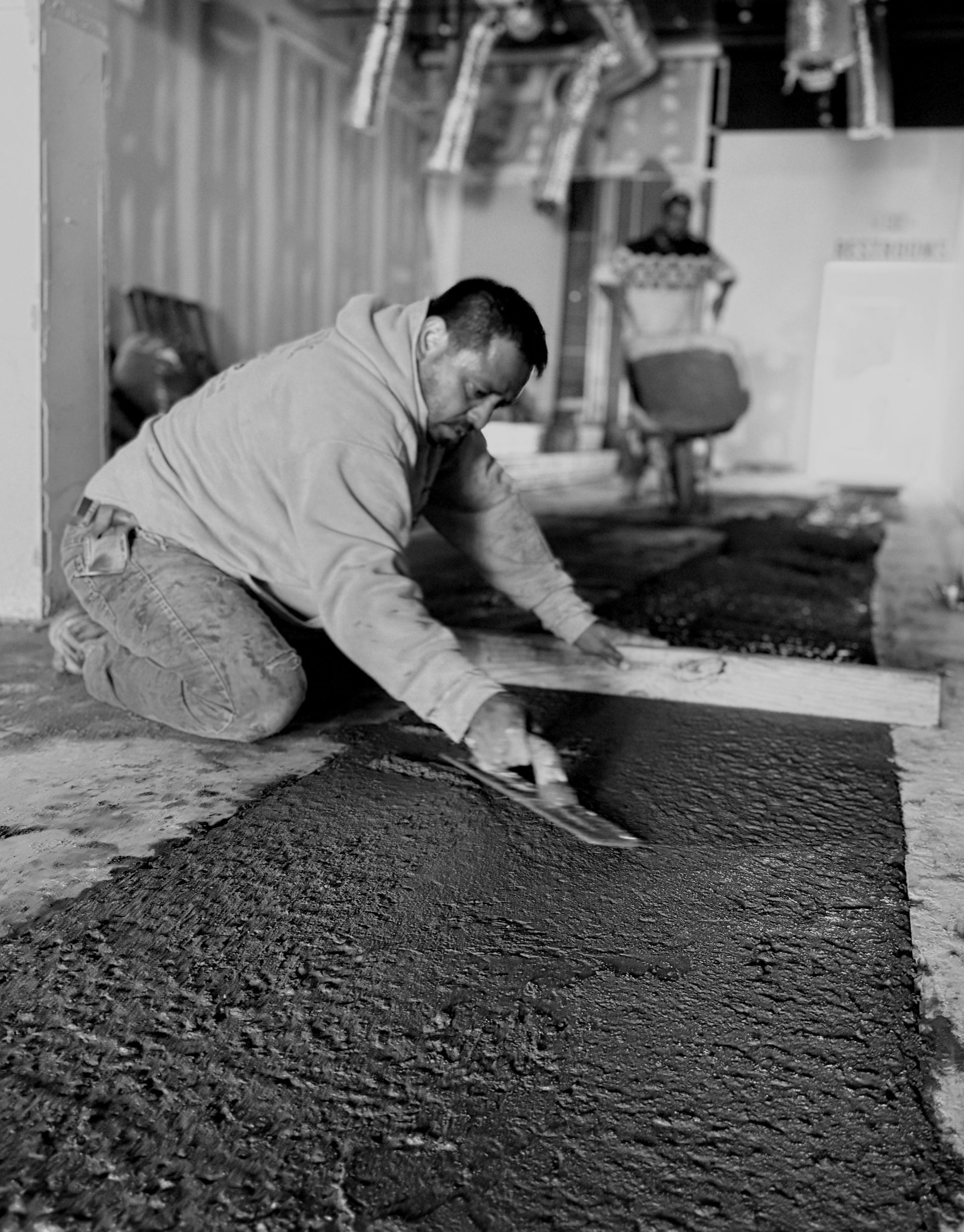 A black and white picture of a worker smoothing material
