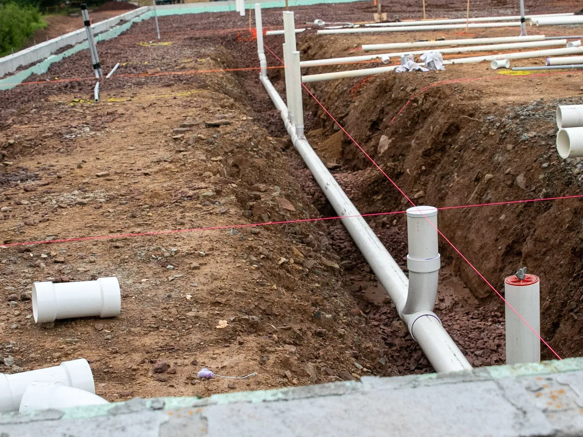 White PVC pipes being installed in a trench at a construction site.