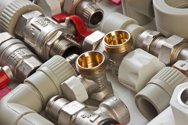 Plumbing fittings: white and brass pipe connectors, valves, and elbows.