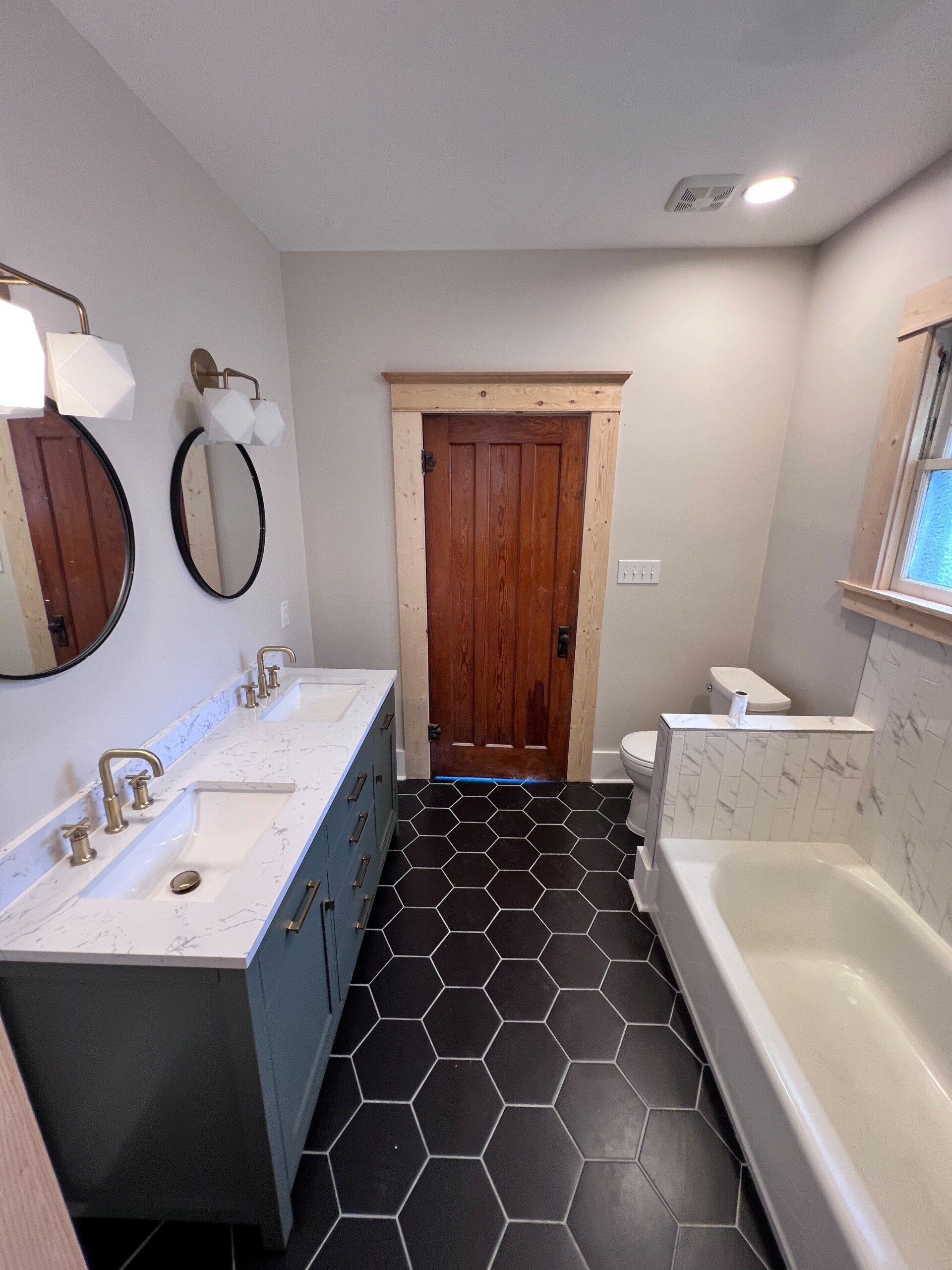 remodeled bathroom with wooden door, marble and black flooring