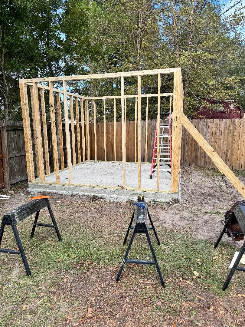 A wooden shed is being built in a backyard.