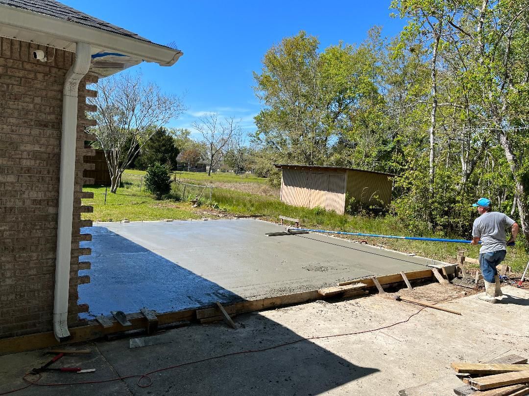 A man is working on a concrete driveway in front of a house.