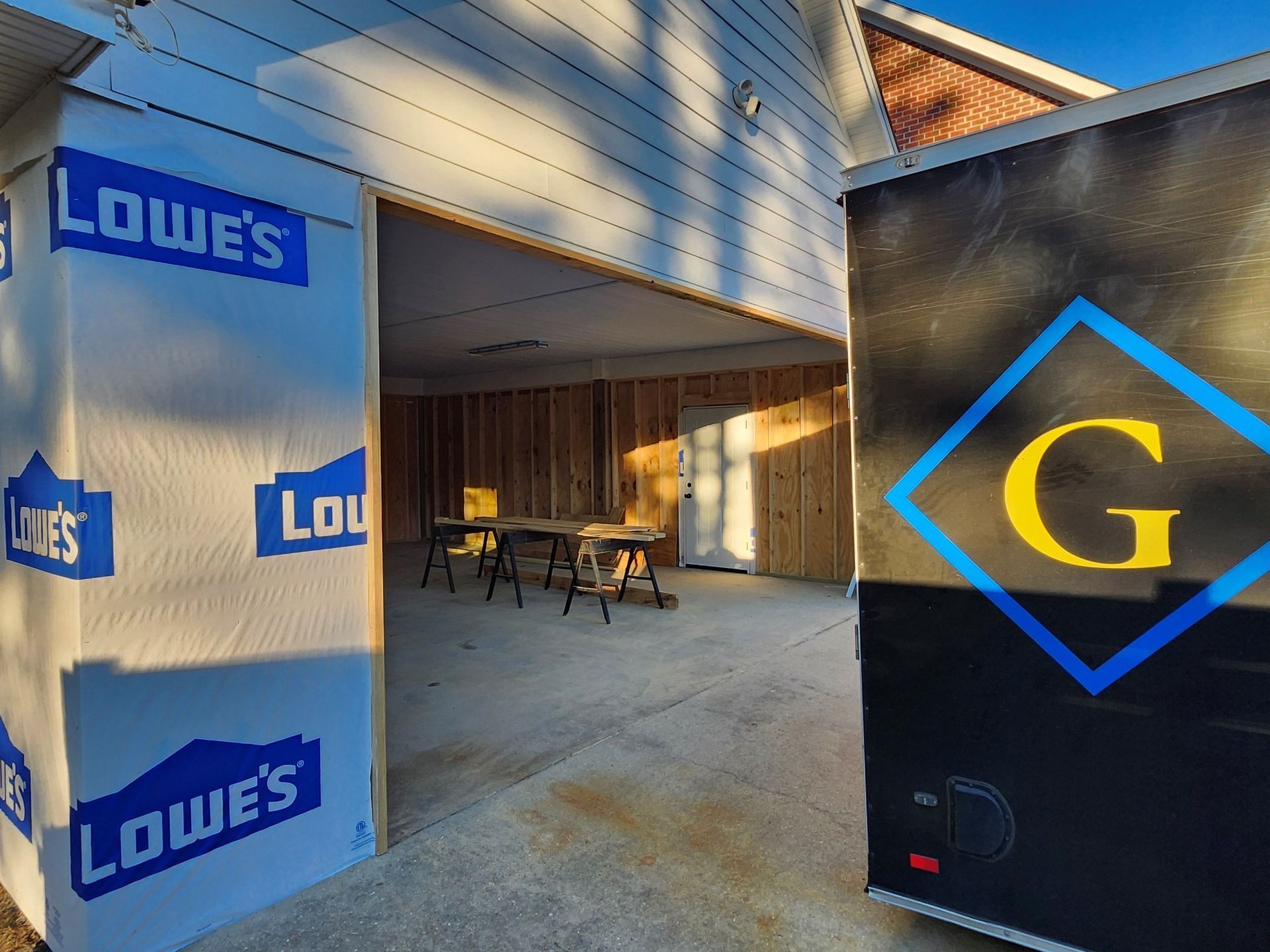 A lowe 's trailer is parked next to a garage under construction