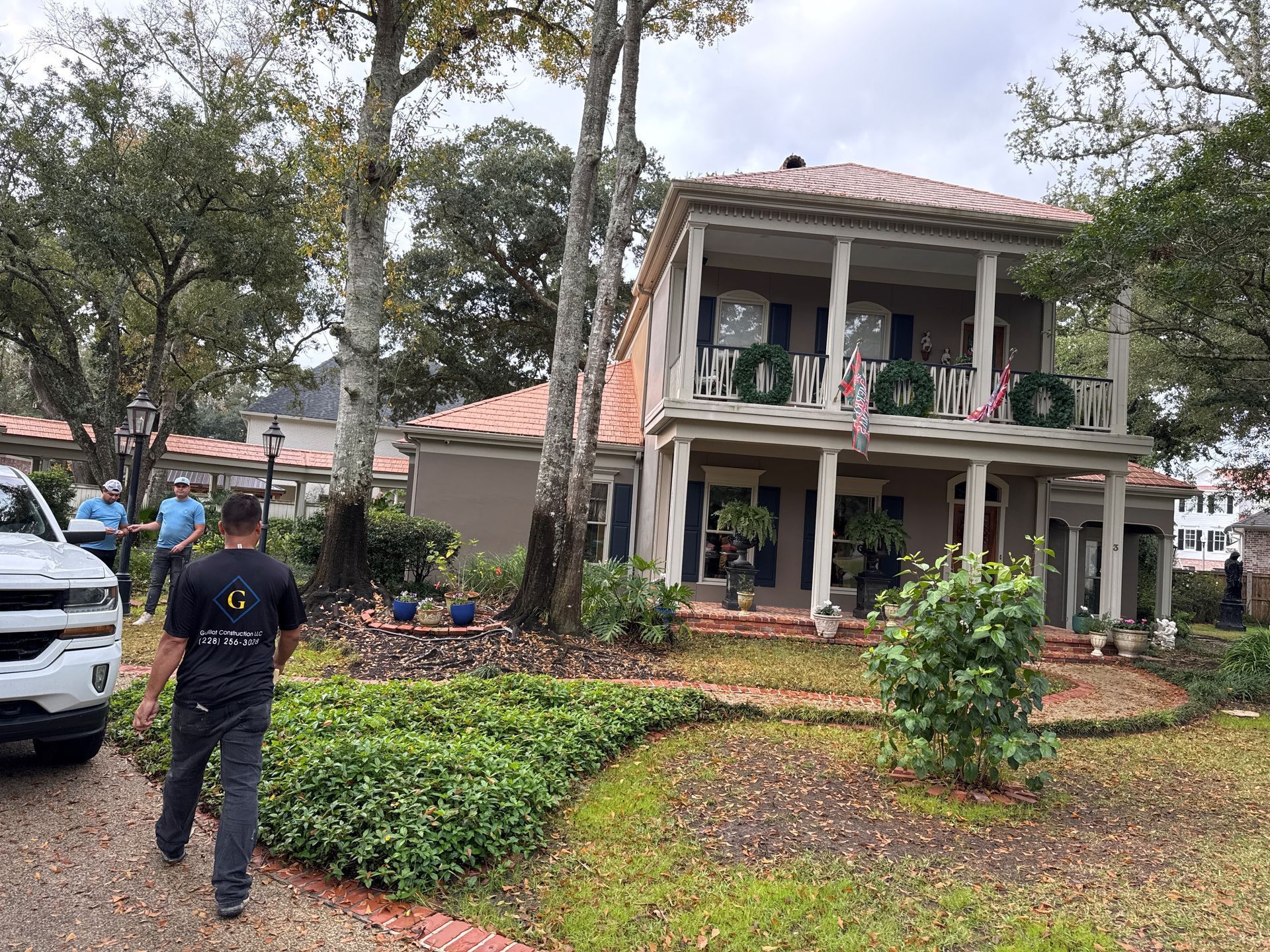 A man is walking in front of a large house decorated for christmas