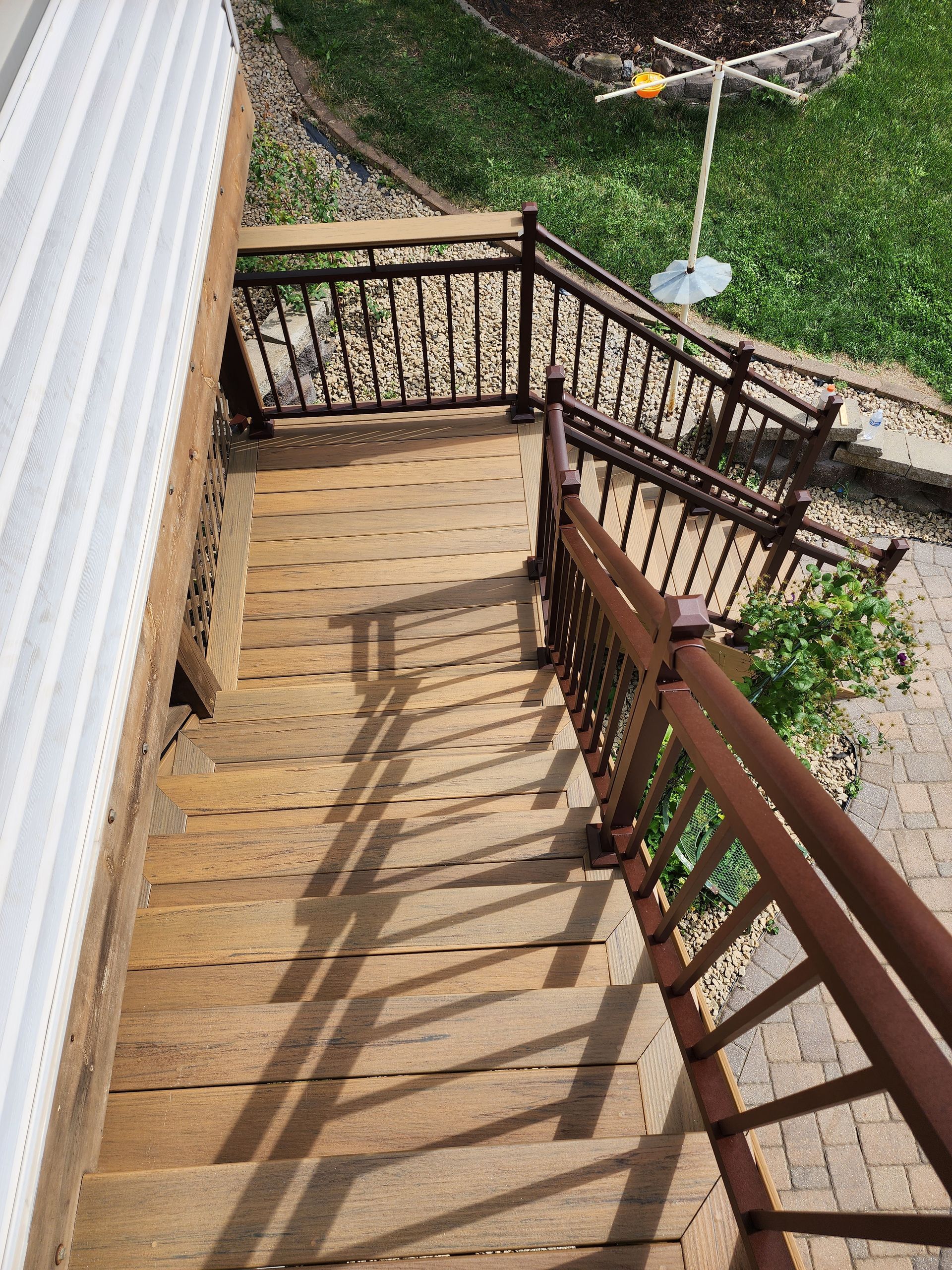 A wooden staircase with a metal railing leading up to a house.