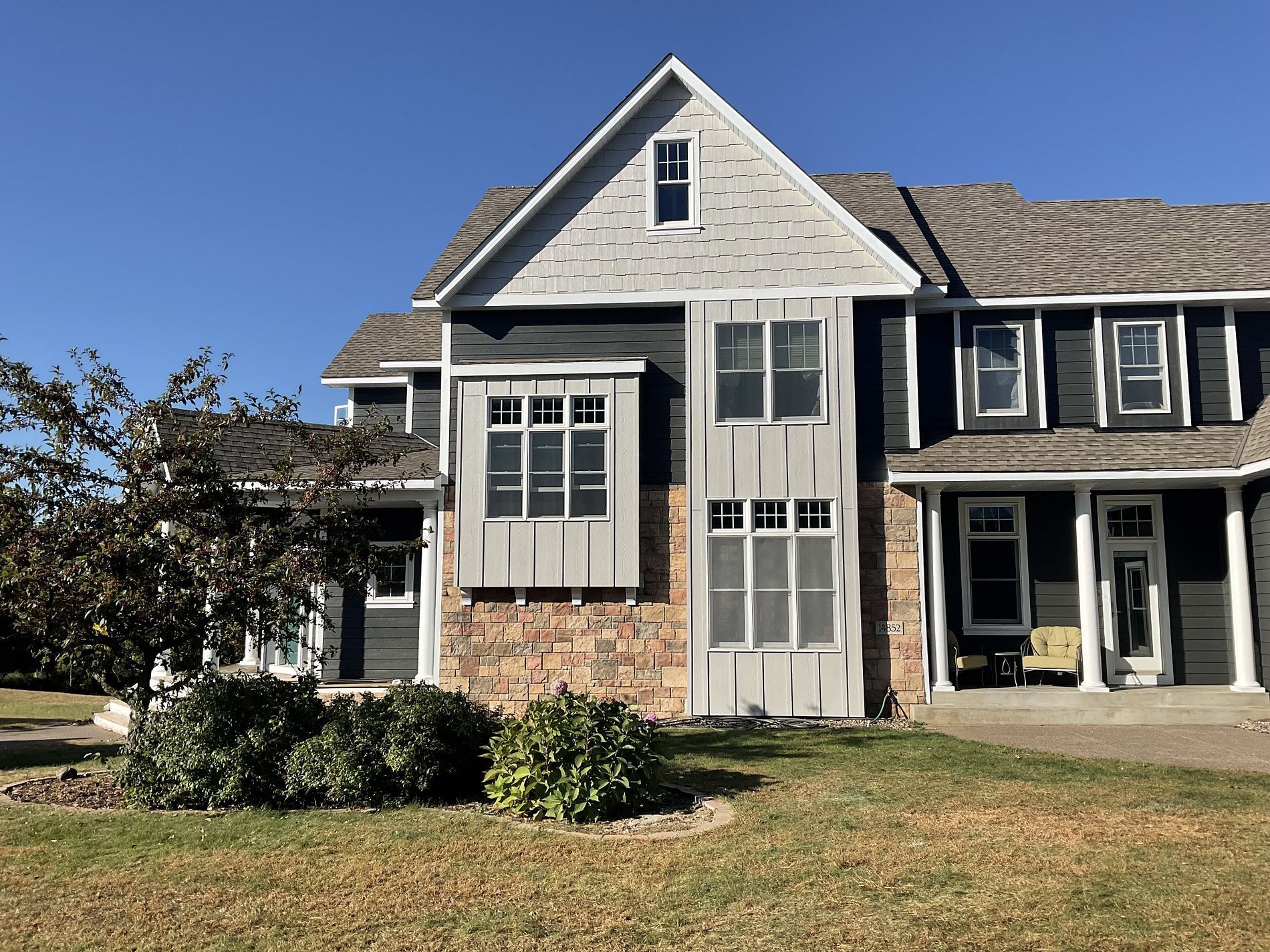 A large house with a lot of windows is sitting on top of a lush green field.