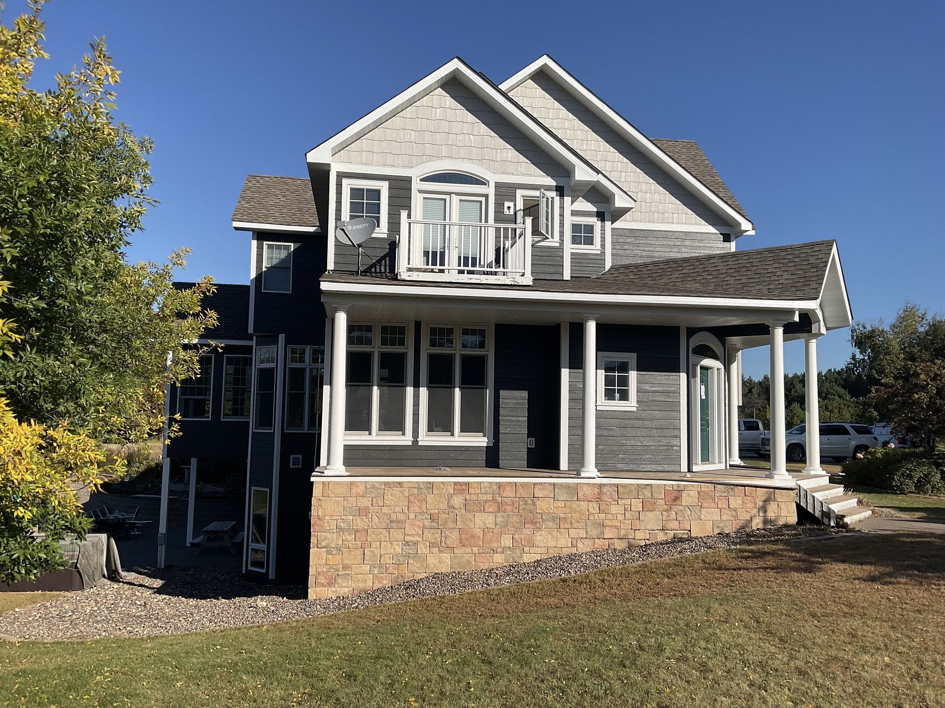 A large house with a large porch and a blue sky in the background.