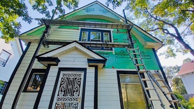 A white house with a green roof is being remodeled.
