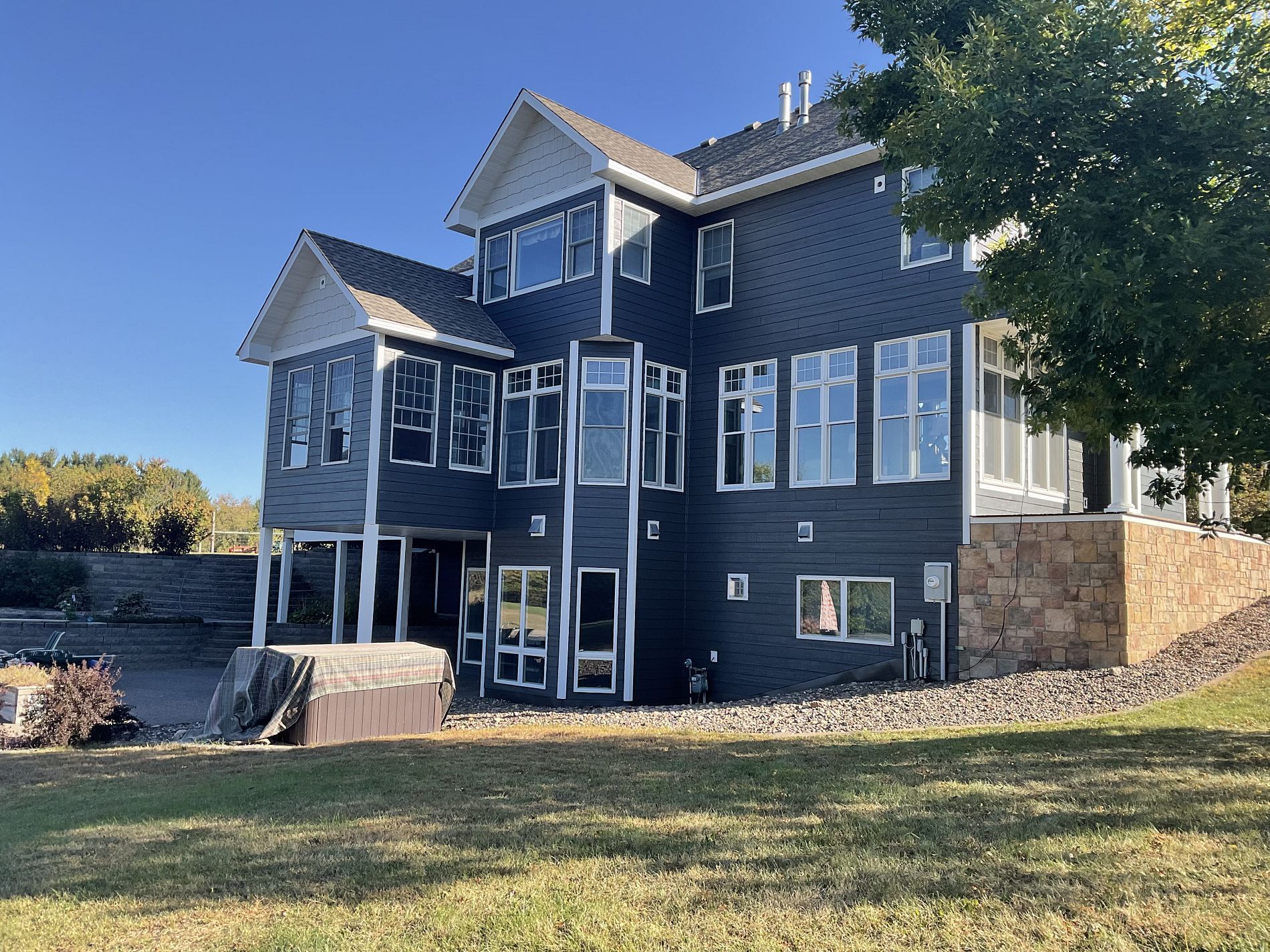 A large house with a lot of windows is sitting on top of a lush green field.