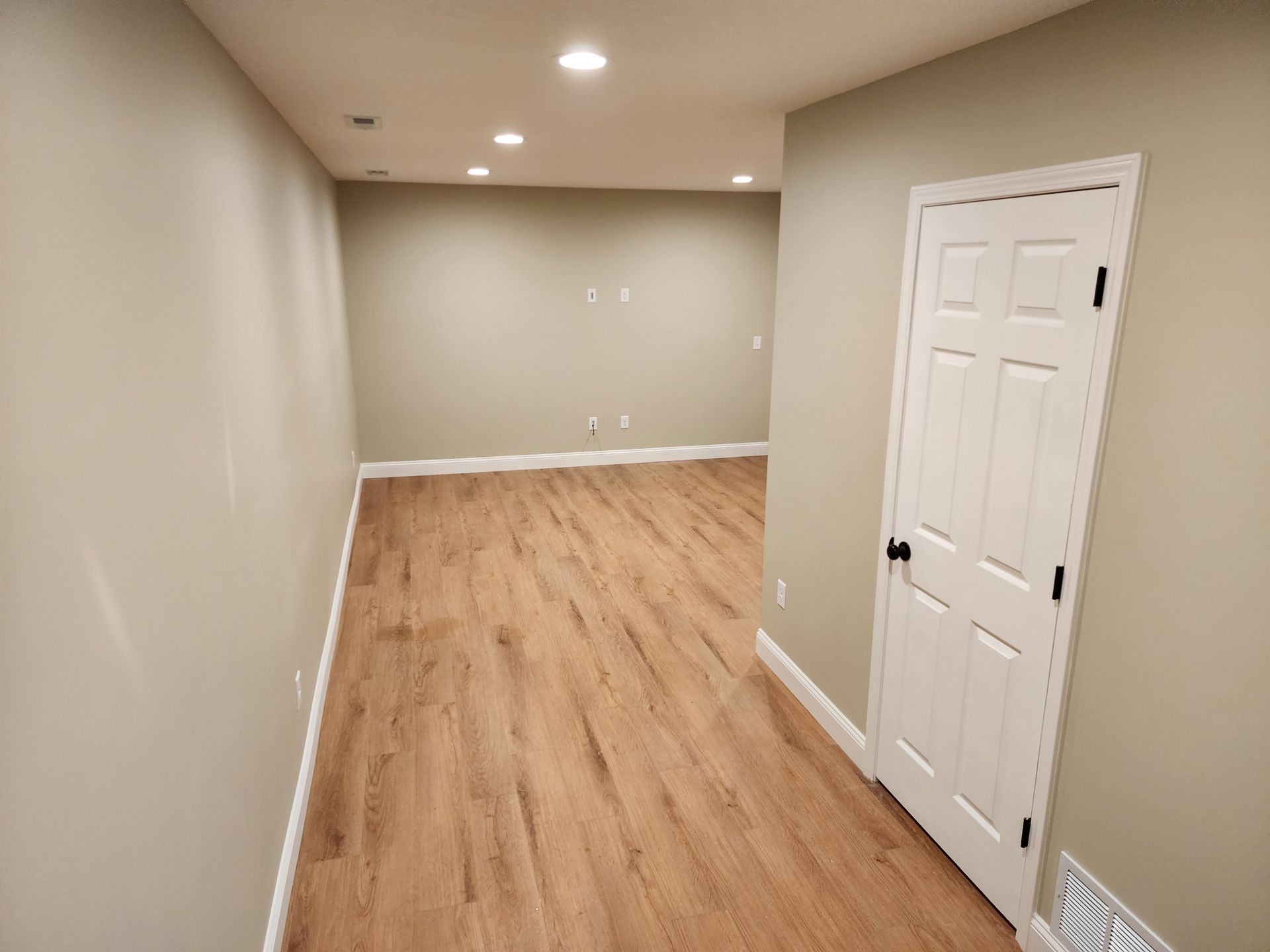 An empty room with hardwood floors and a door