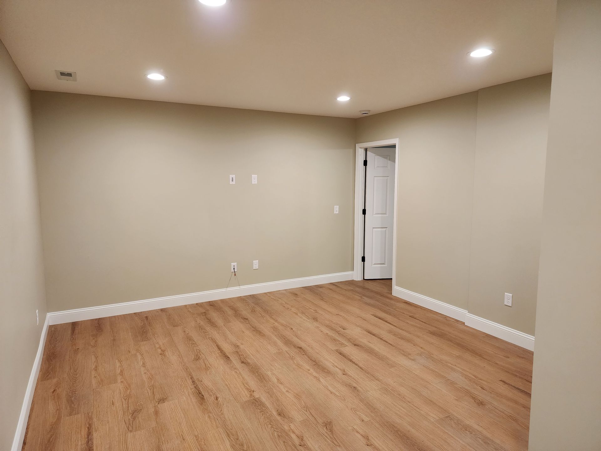 An empty room with hardwood floors and beige walls.