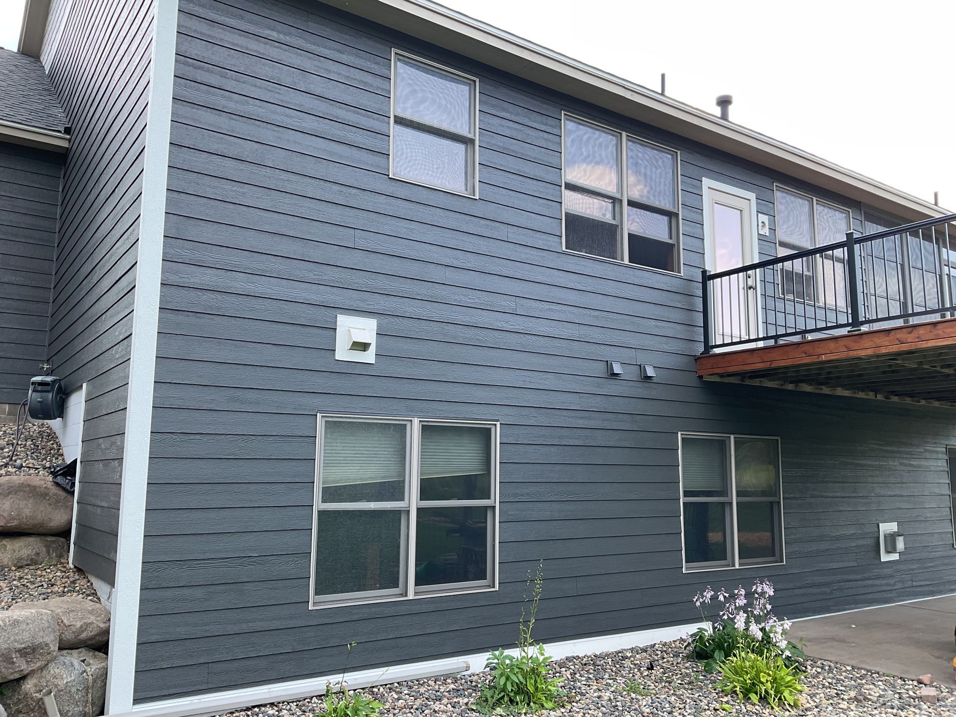 A large gray house with a balcony and a lot of windows.