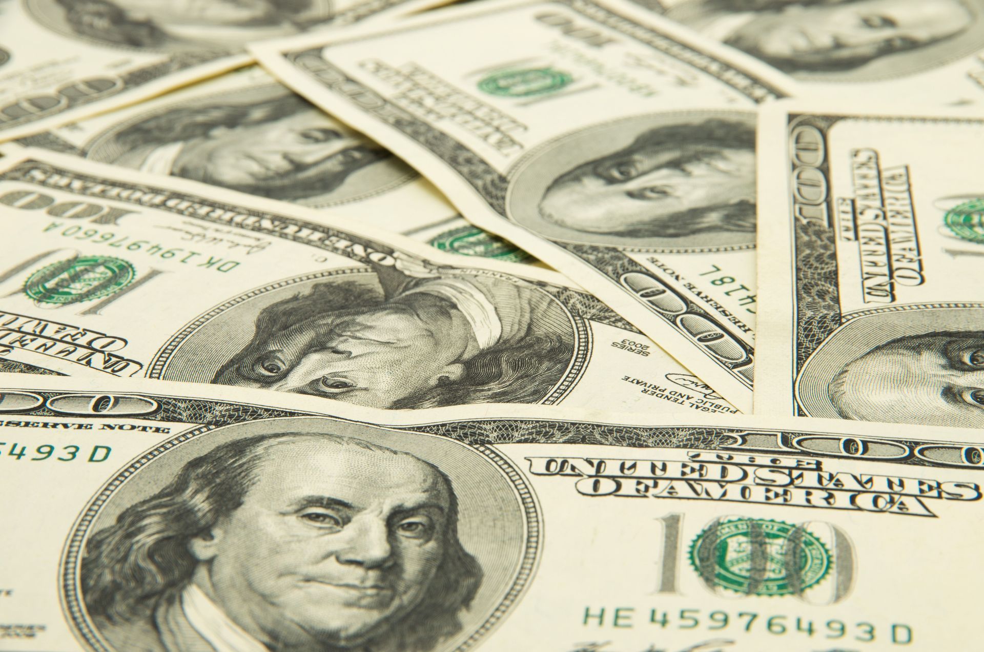 Scattered U.S. $100 bills arranged in a close-up view