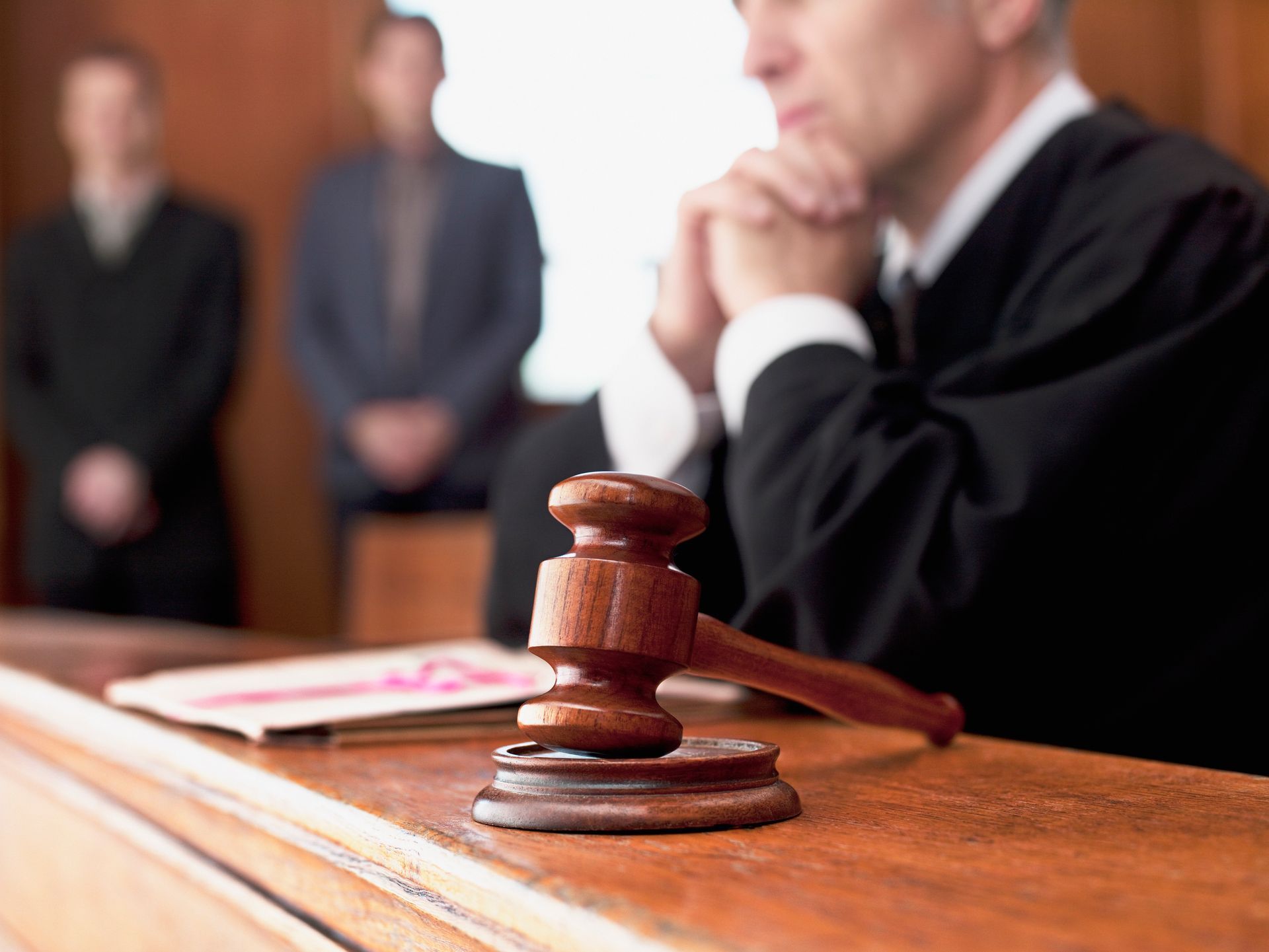Judge’s gavel on a courtroom bench with a blurred attorney and people in the background