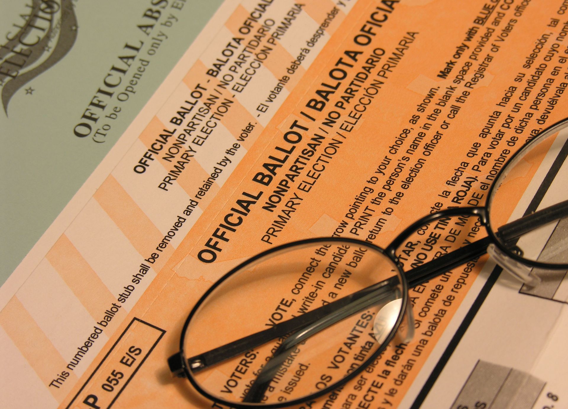 Ballot papers and eyeglasses on a desk, with one official ballot form visible