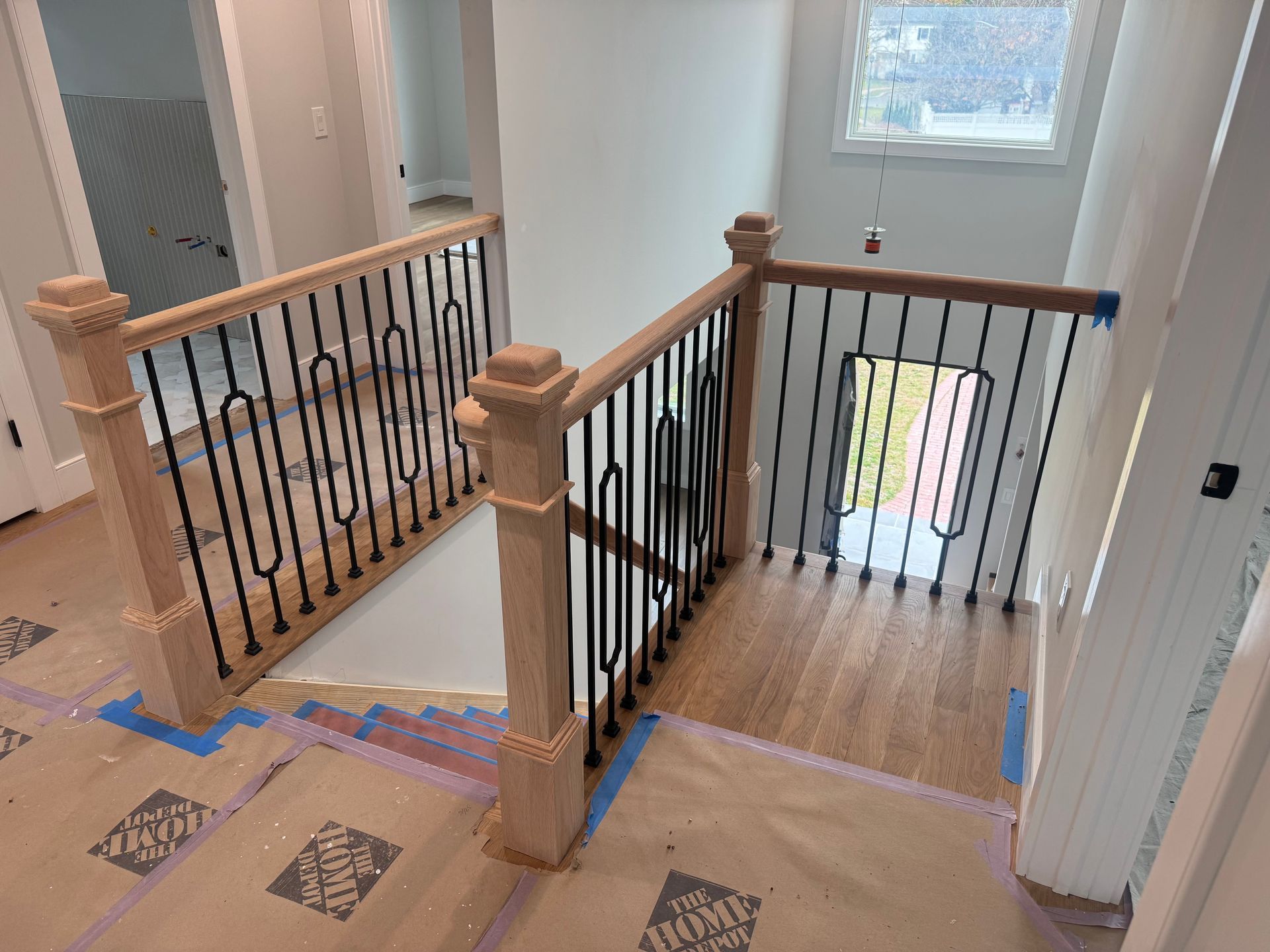 Wooden staircase with black metal railings, leading to a lower level.