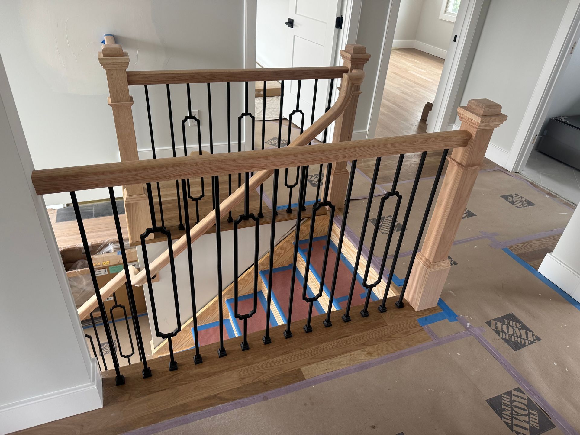 Wooden staircase with black metal railing and light wood floor.