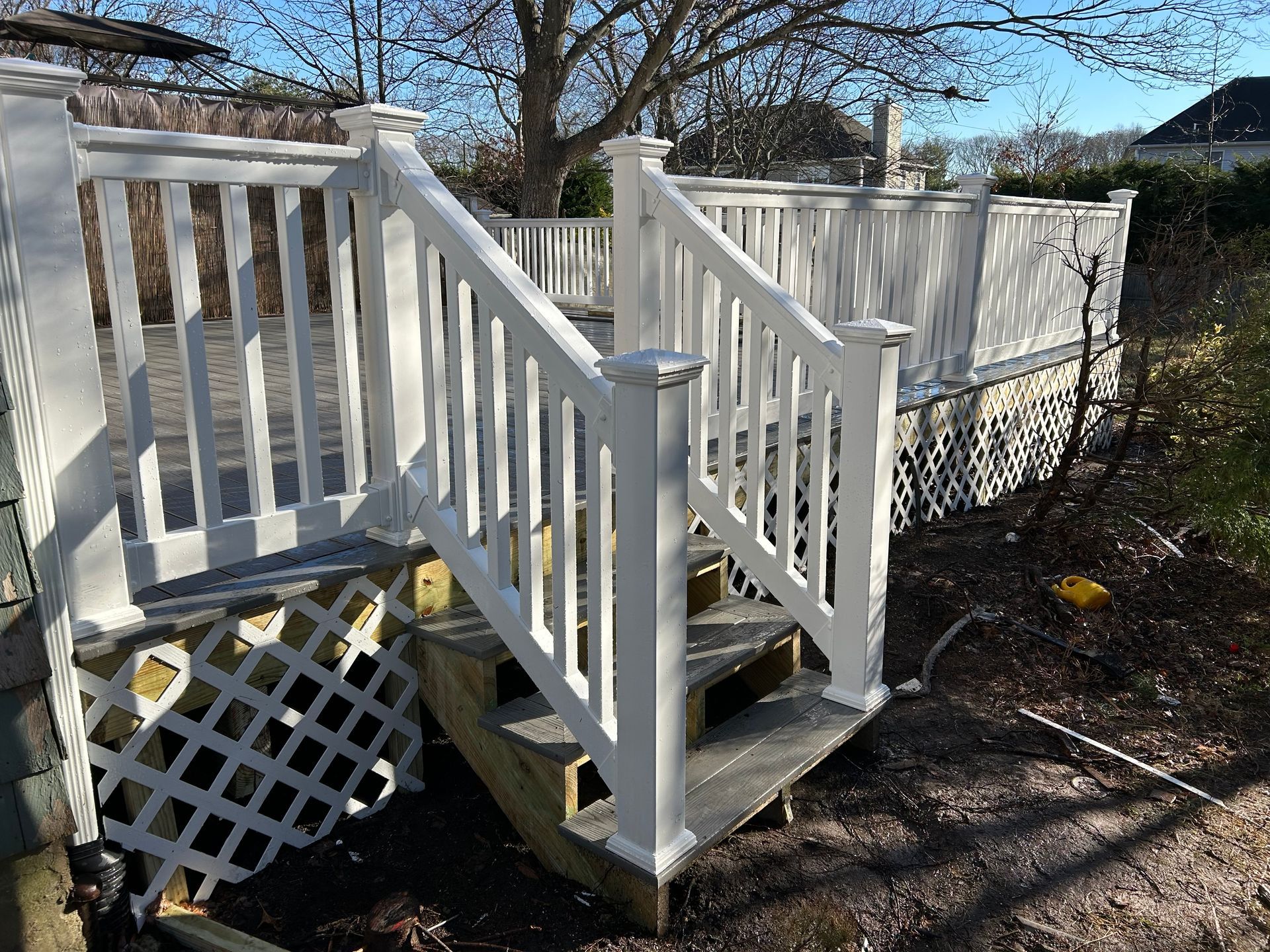 White painted wooden deck with railing, lattice undercarriage, steps.