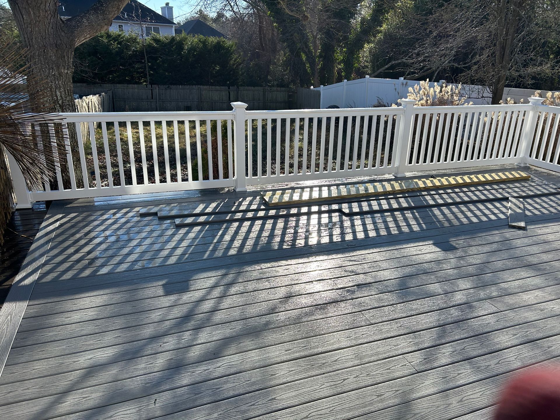 Grey deck with white railing, casting long shadows.