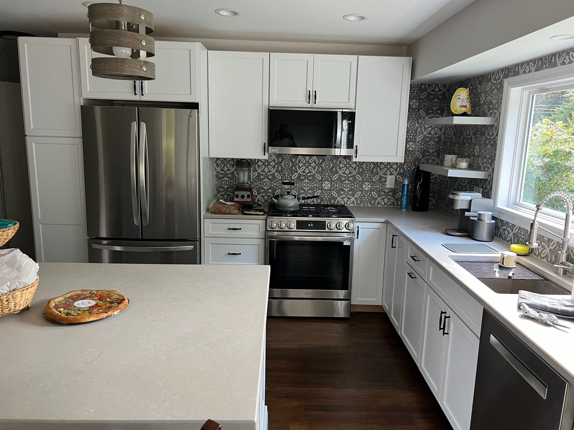 White kitchen with stainless steel appliances, white cabinets, and light countertops.