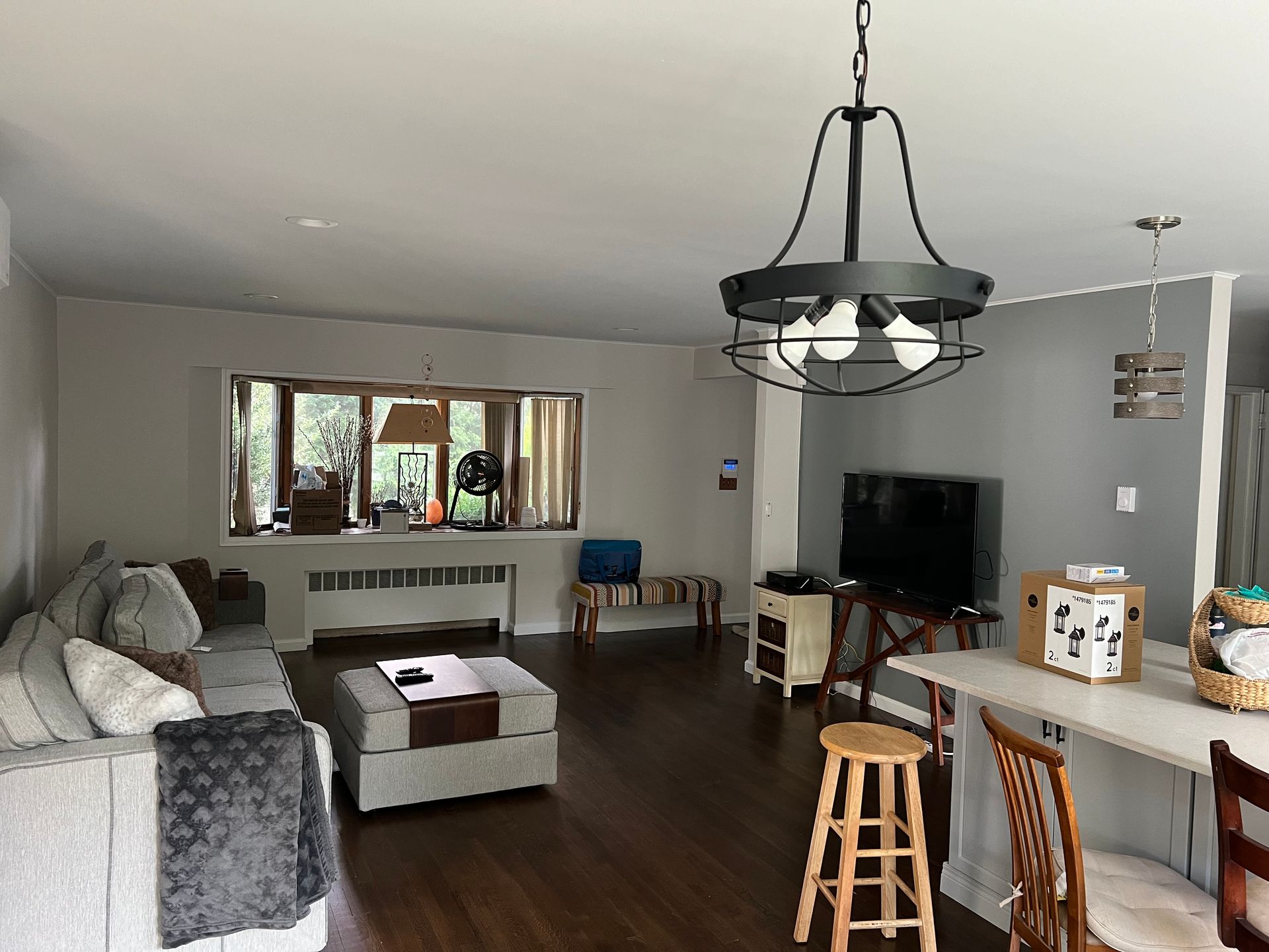 Open-concept living space with a sectional sofa, TV, and dining area, hardwood floors, and overhead lighting.