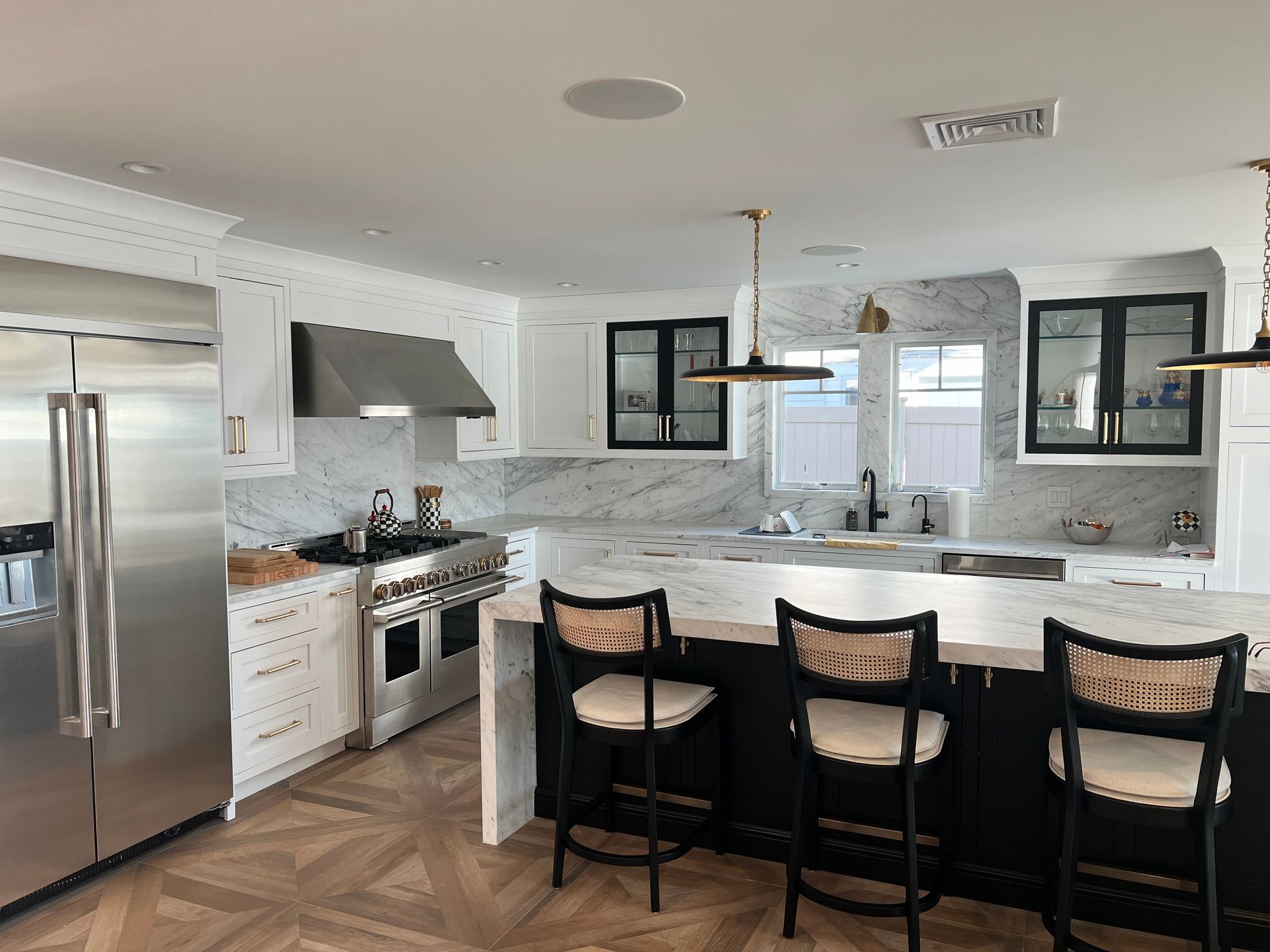 Modern kitchen with stainless steel appliances, white cabinets, and a black island with bar stools.