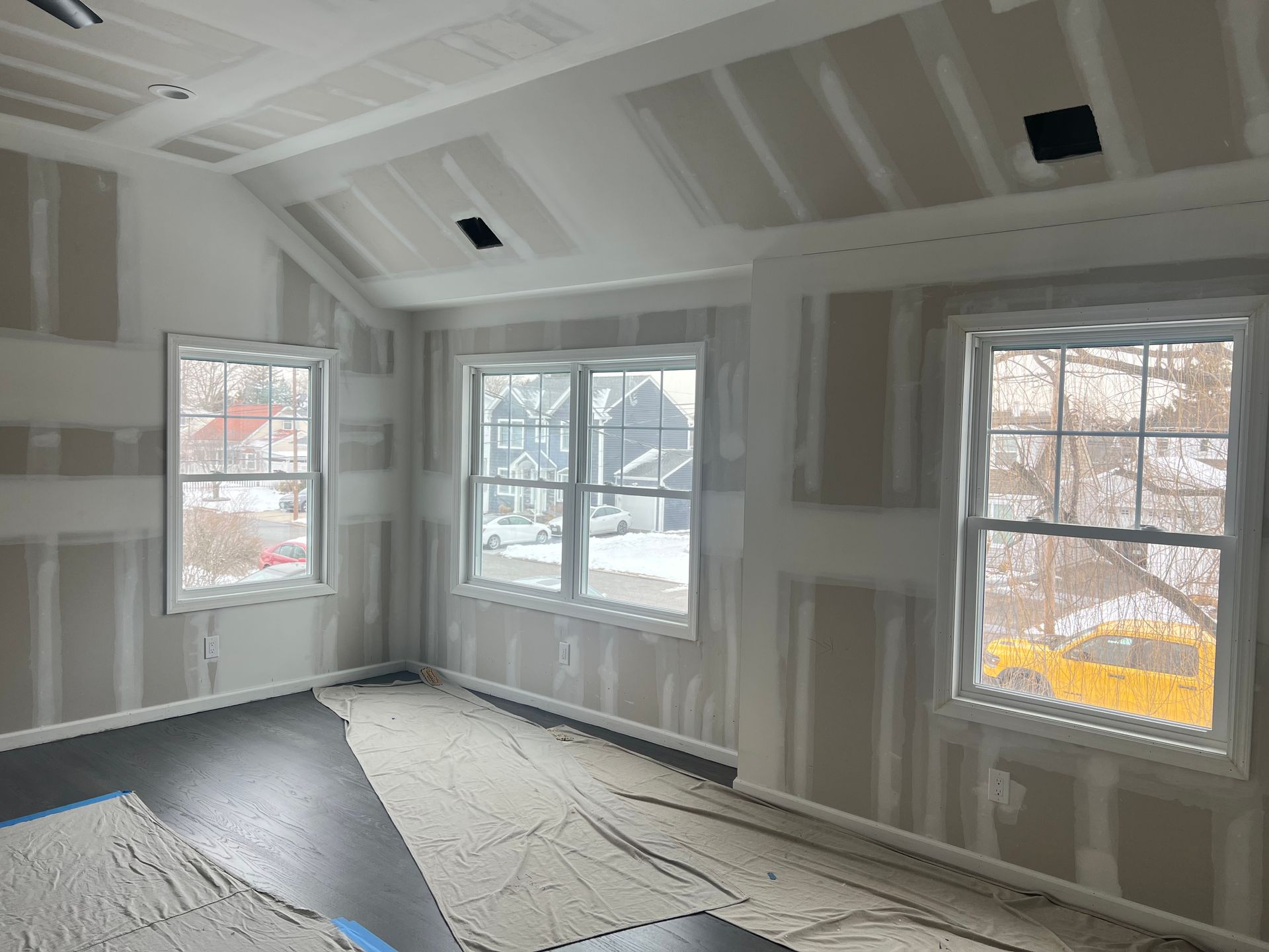 Room interior under construction with drywall and windows.