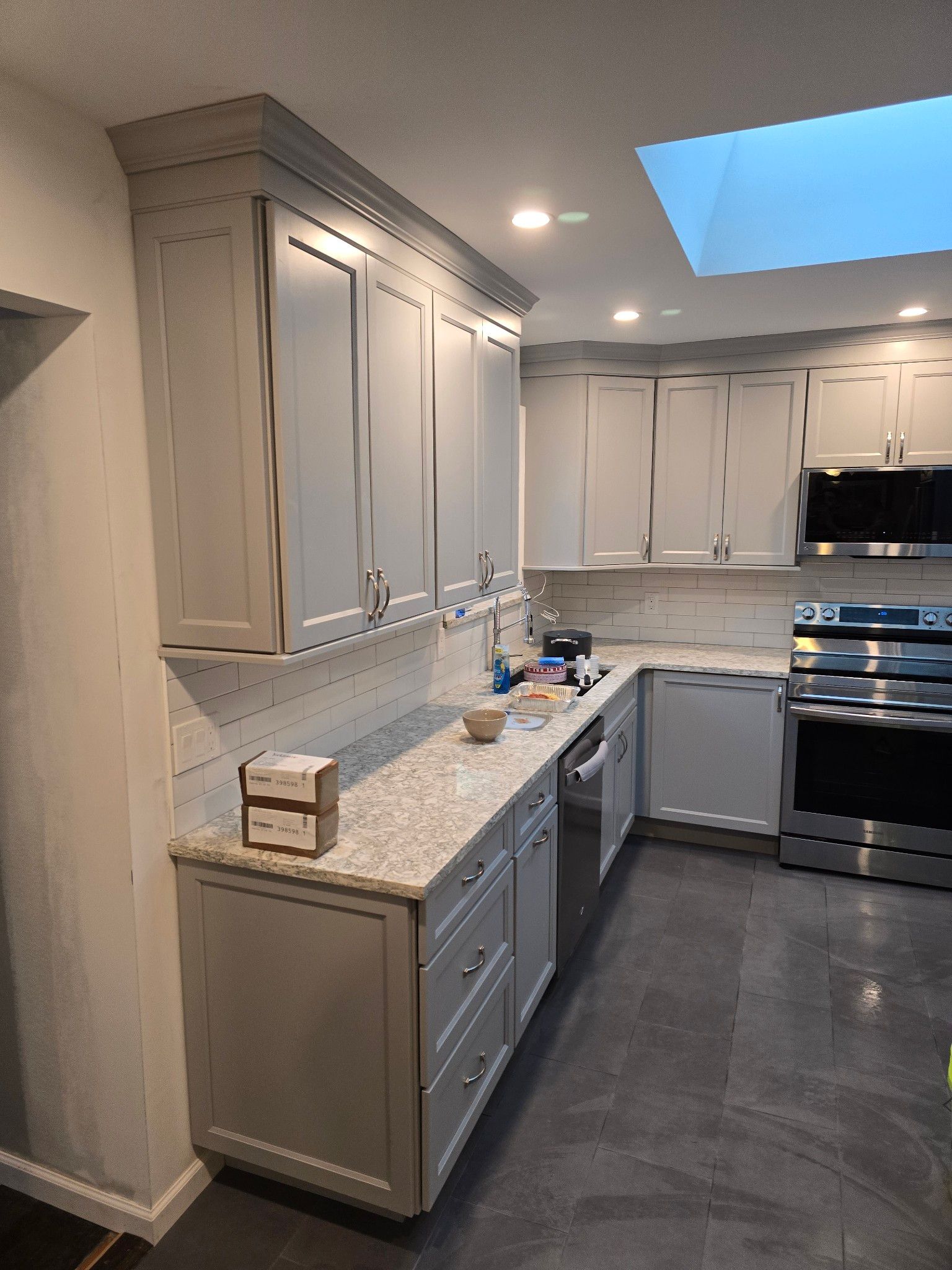 Gray kitchen cabinets with a granite countertop and stainless steel appliances.
