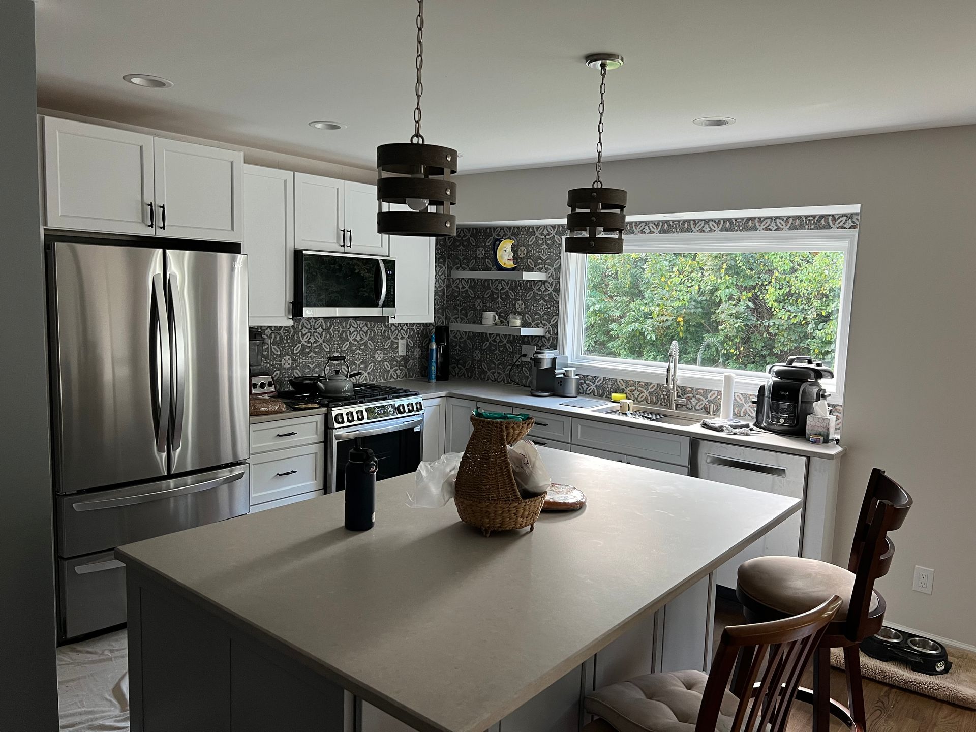 Modern white kitchen with stainless steel appliances, island, and pendant lights.