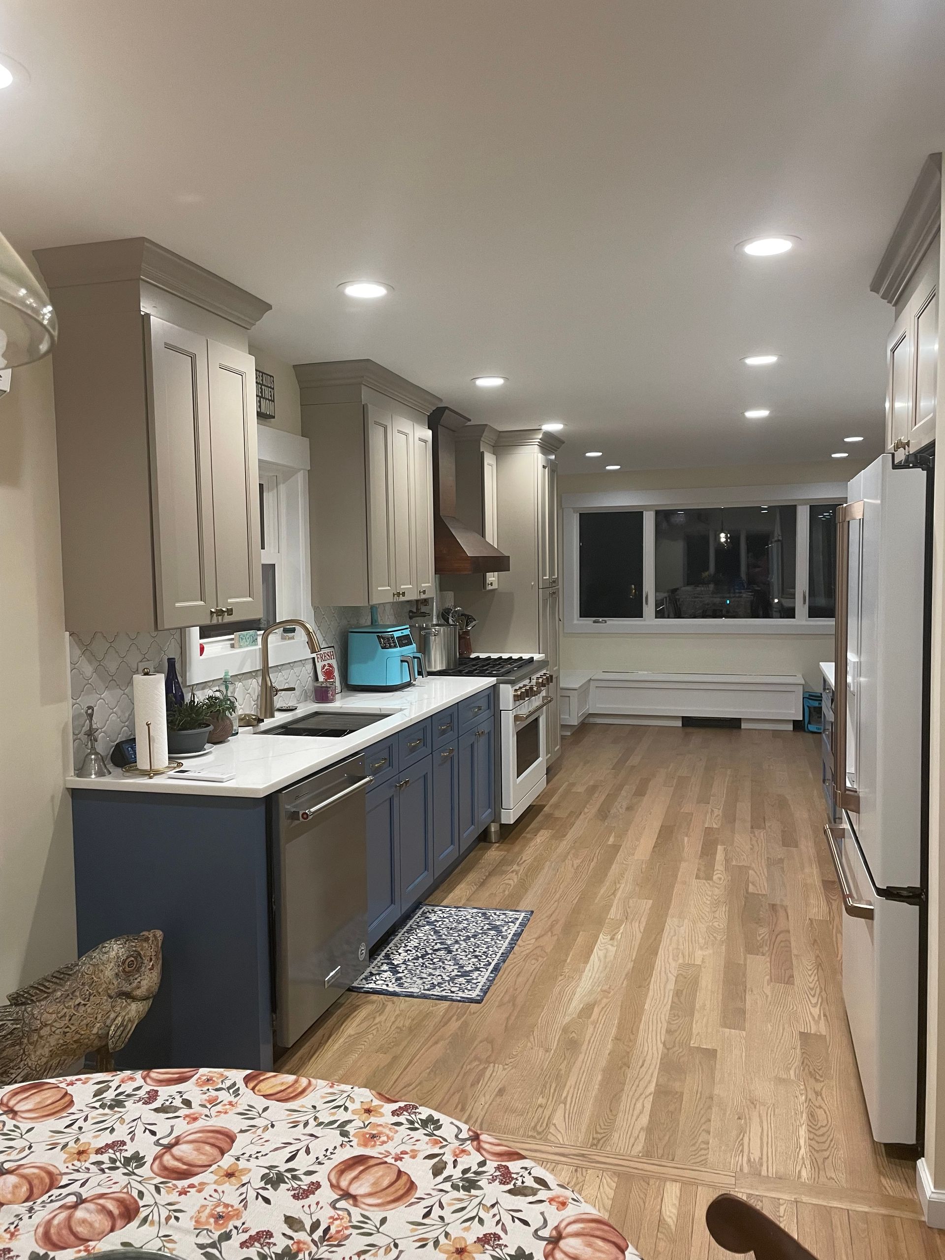 Kitchen with gray and blue cabinets, stainless steel appliances, and wood floor.
