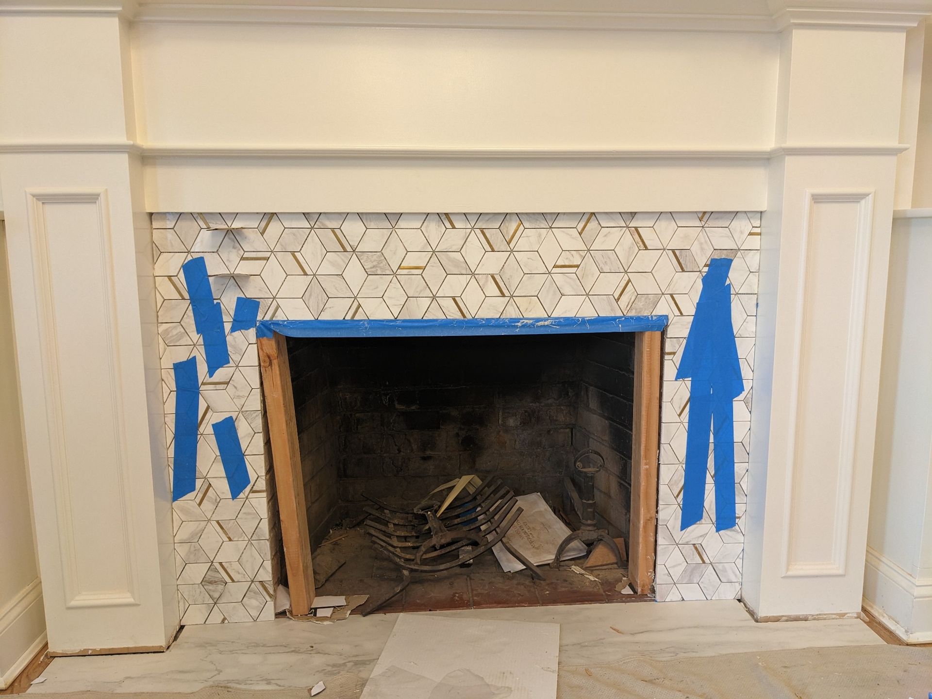 Fireplace with white mantle, geometric tile surround, and open firebox.