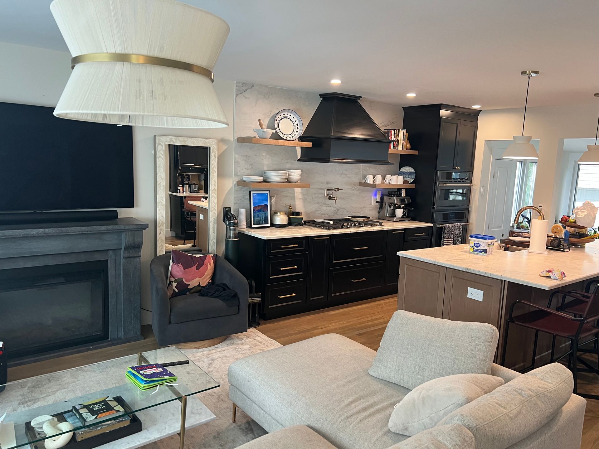 Open-concept kitchen and living area with black cabinets, white countertops, and a fireplace.