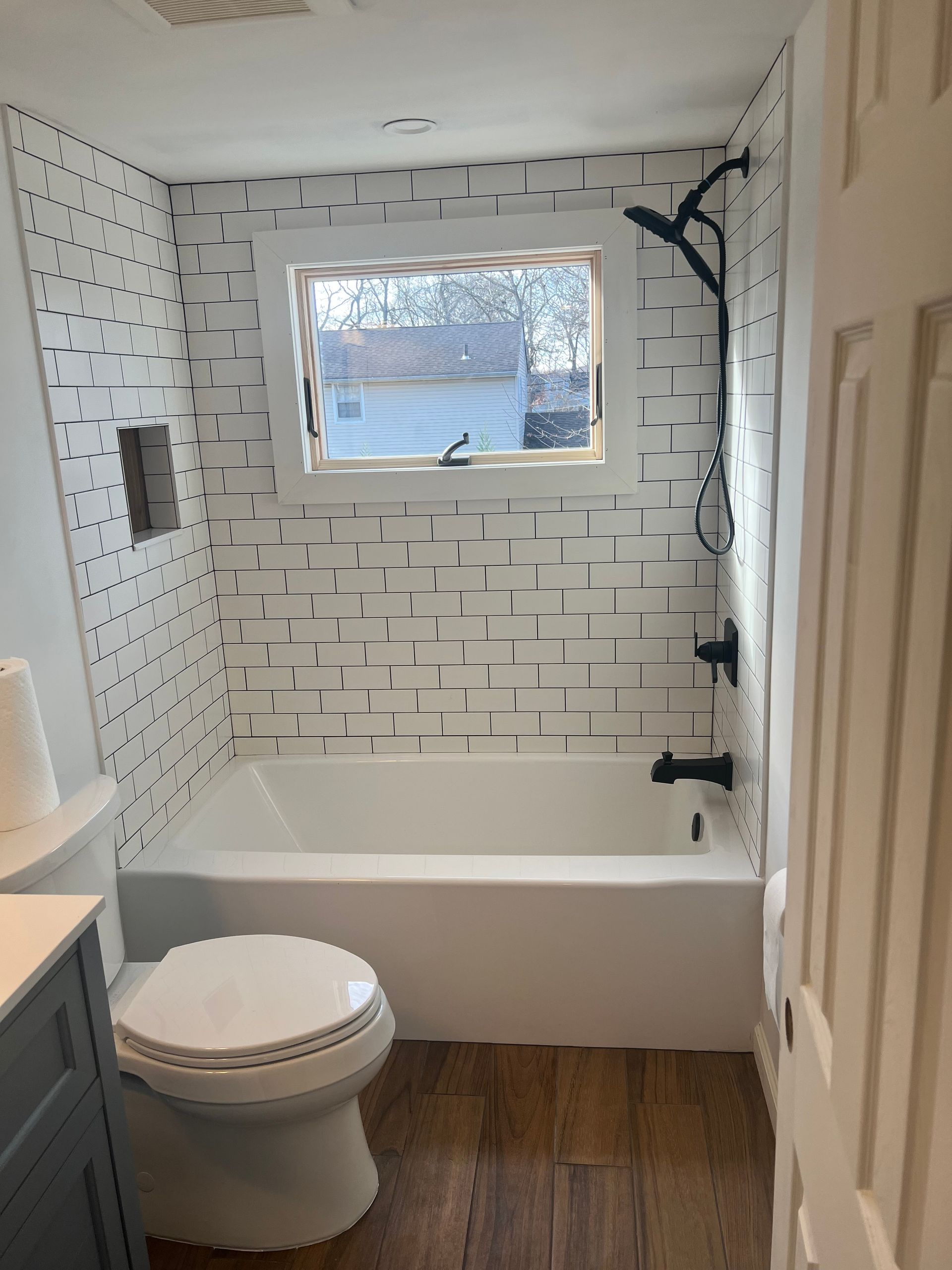 Bathroom with white bathtub, black fixtures, and patterned white and black tile.