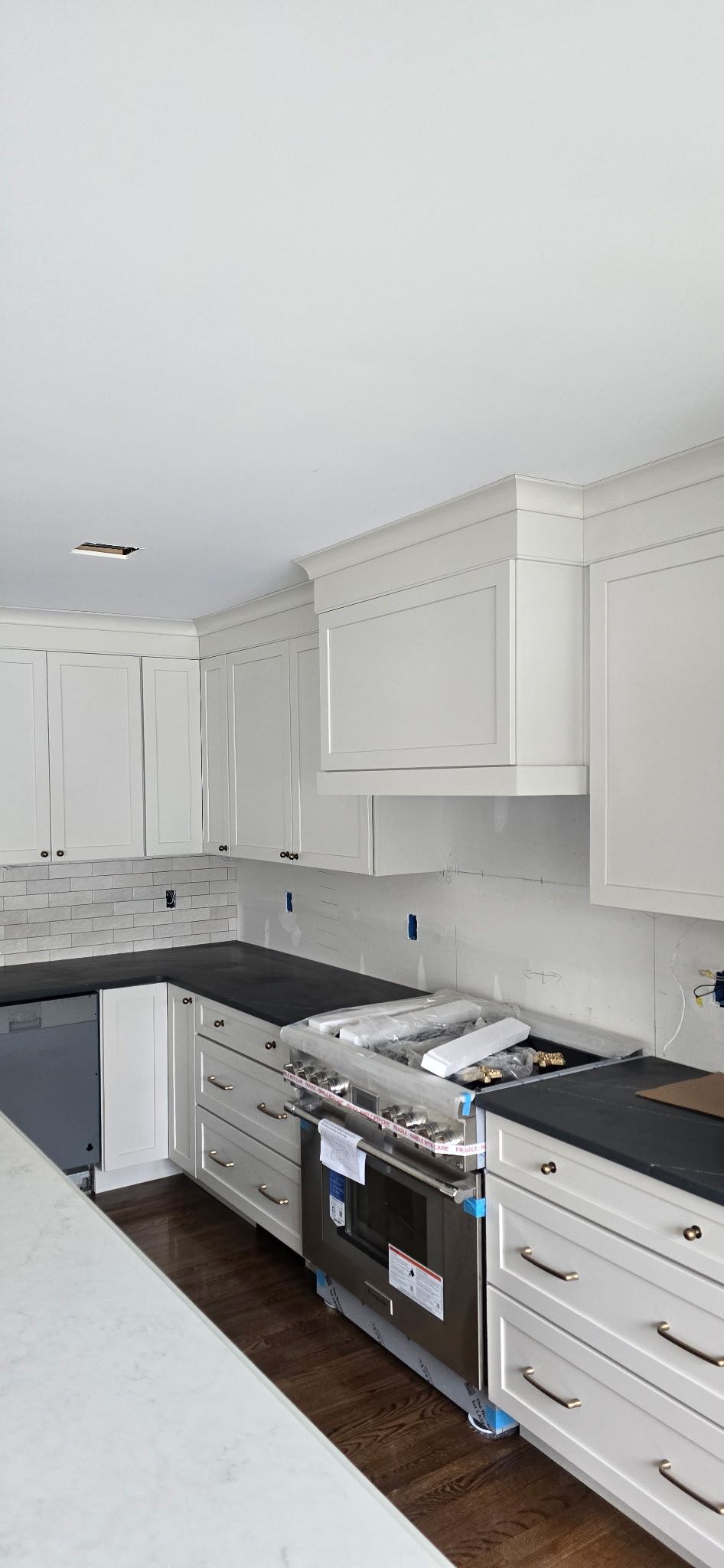 White kitchen cabinets with black countertops and a stainless steel oven.