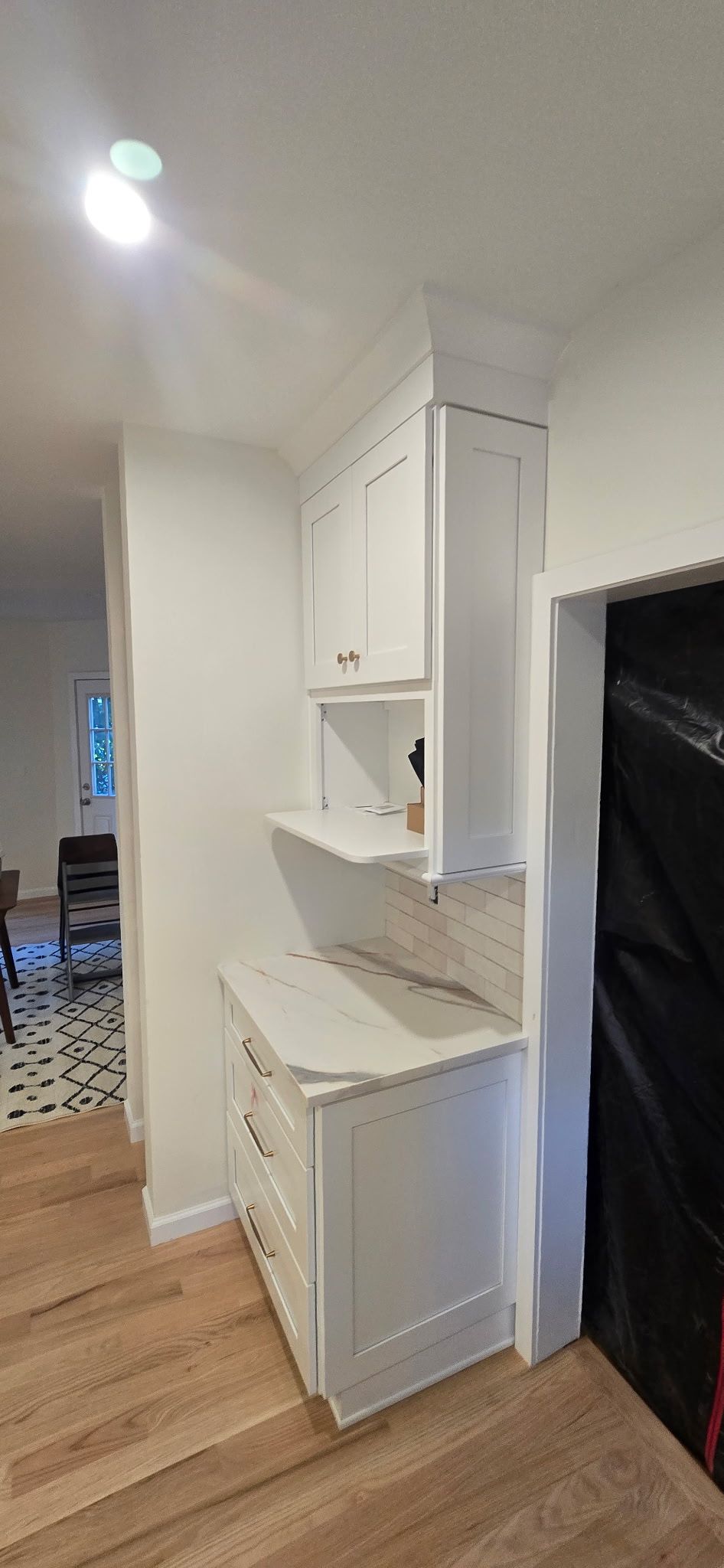 White built-in cabinetry with countertops and shelves, with a doorway on the right and entryway on the left.