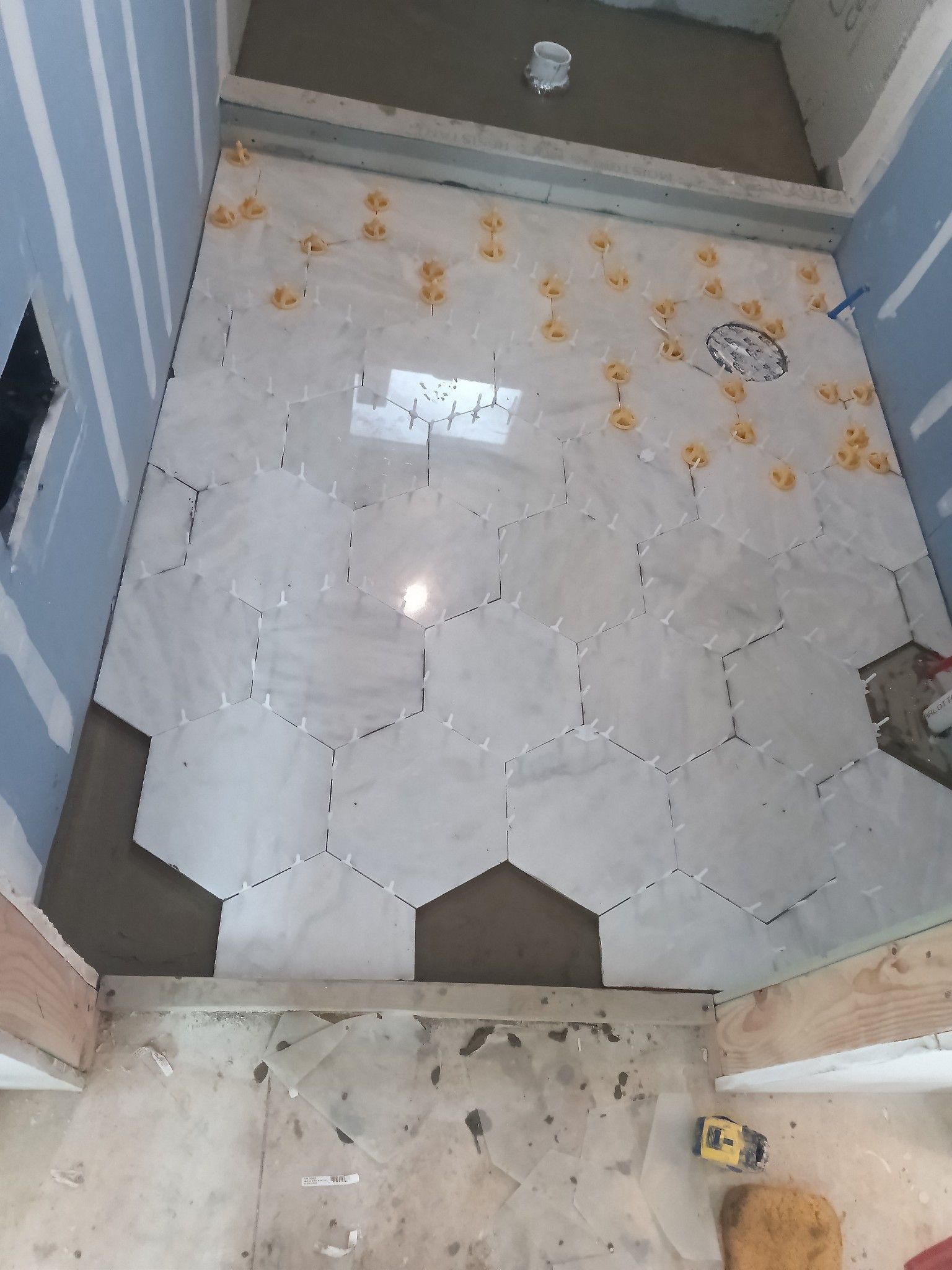Bathroom floor tiled with large hexagonal tiles; tile spacers are visible.