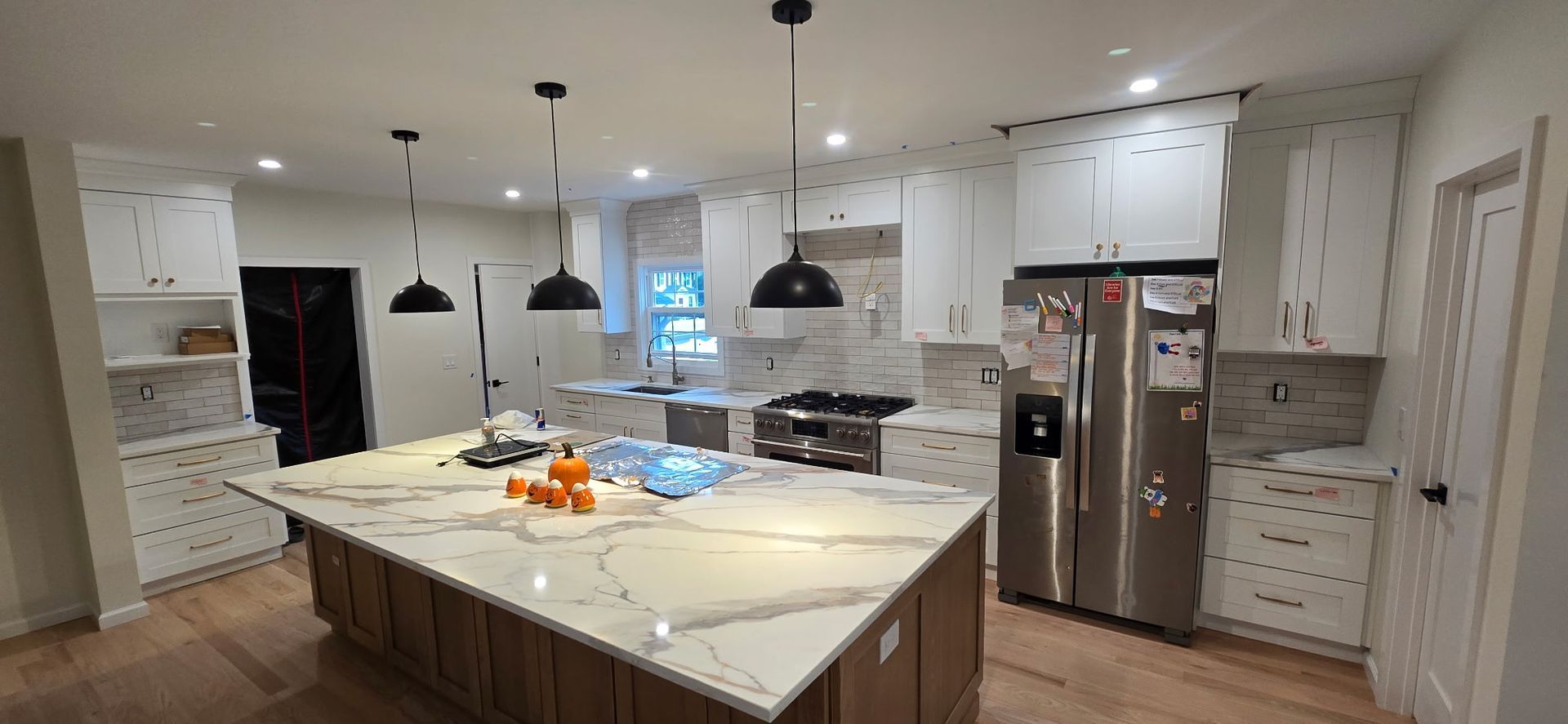 Newly renovated kitchen with a large island, stainless steel appliances, and white cabinets.