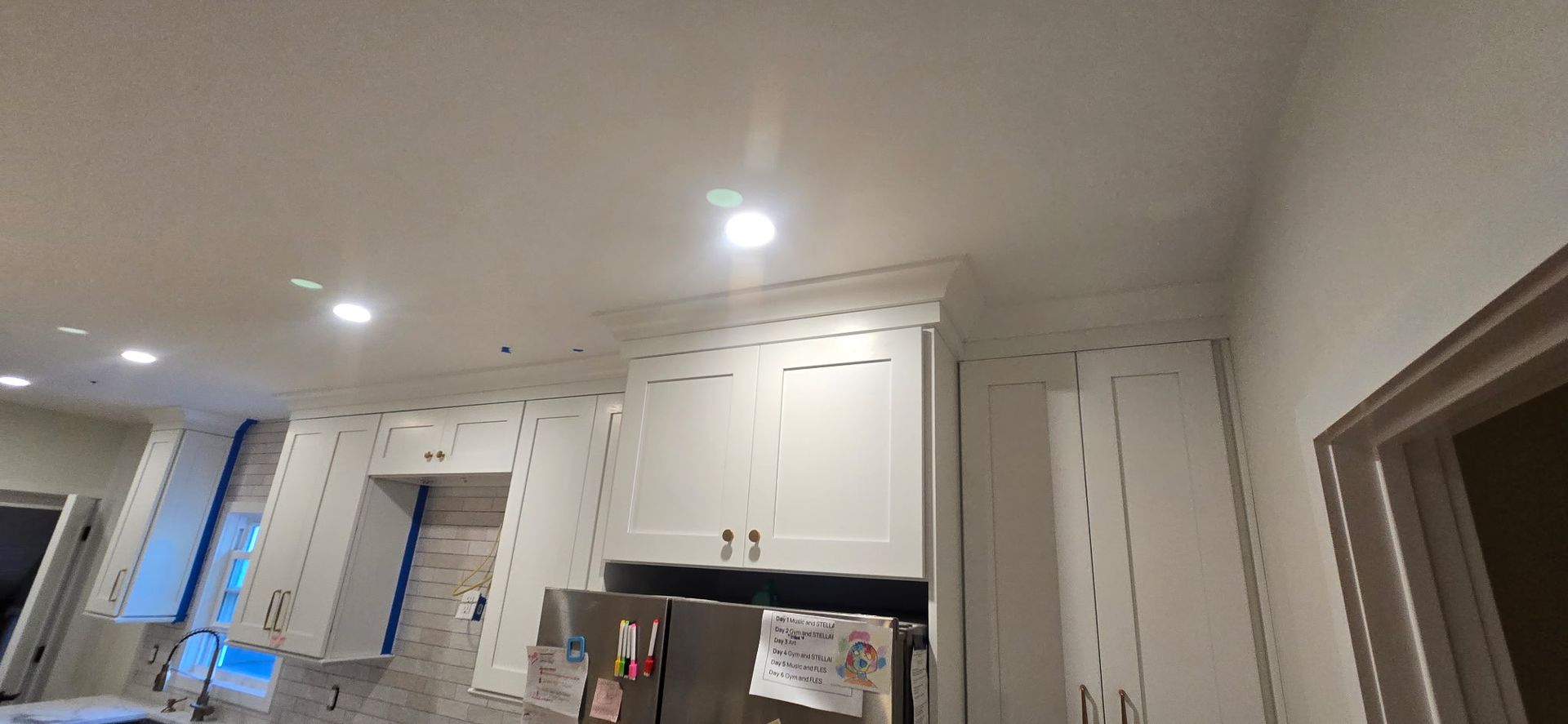 White kitchen cabinets with crown molding and stainless steel refrigerator.