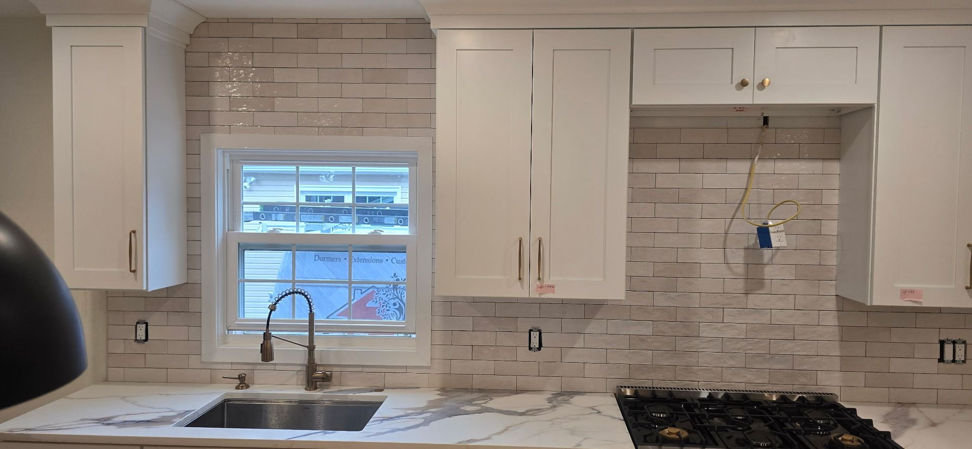 Kitchen remodel with white cabinets, light tile backsplash, and marble countertops.