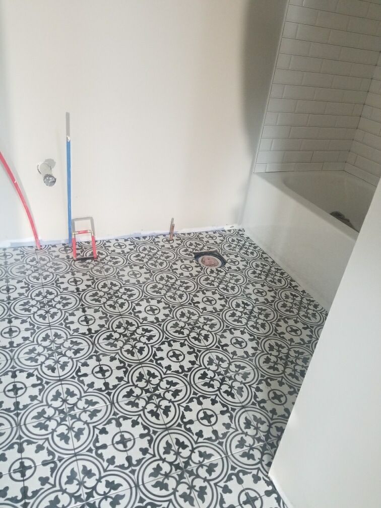 Bathroom under construction with black and white patterned tile flooring.