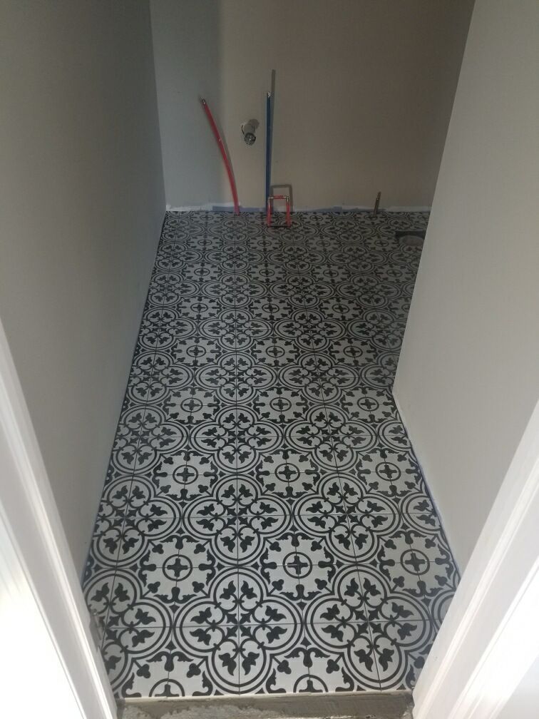 Narrow hallway with black and white patterned tile flooring. Plumbing visible at the back.