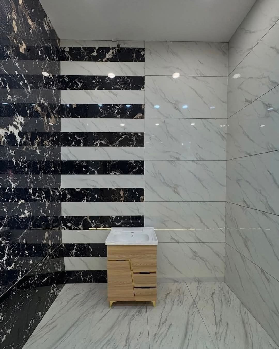 Bathroom with black and white marble tile walls and a wooden vanity.