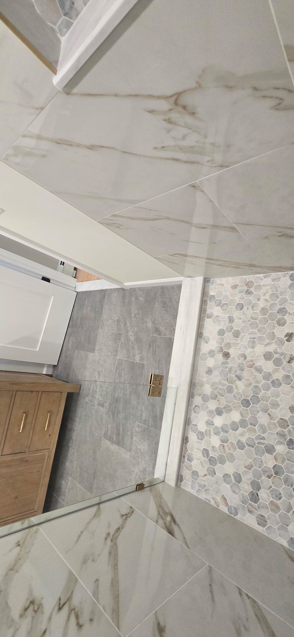 Bathroom interior with marble tile floors, a mosaic tile accent wall, and a wooden cabinet.