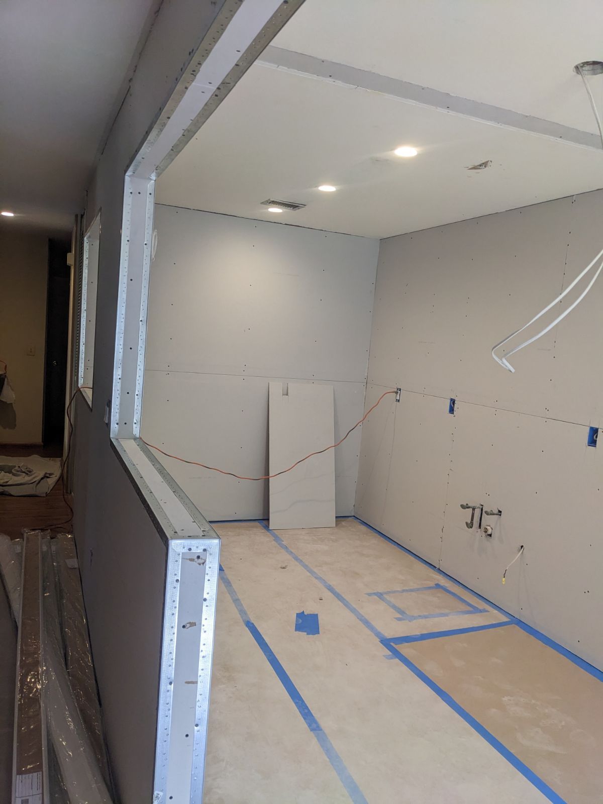 Interior view of a kitchen under construction with drywall and electrical wiring exposed.