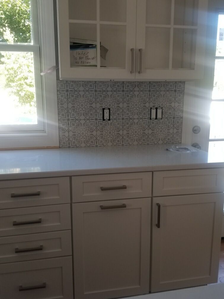 Kitchen cabinets with a tiled backsplash, countertop, and window.