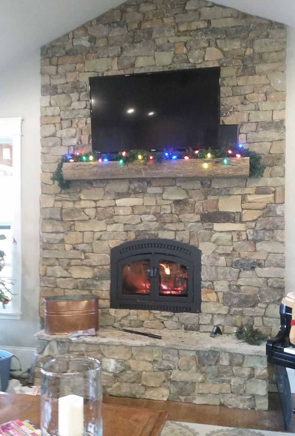 A living room with a stone fireplace and a flat screen tv.