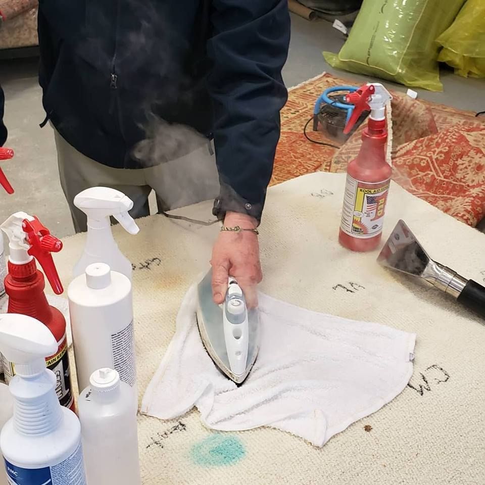 A man is using an iron to clean a carpet