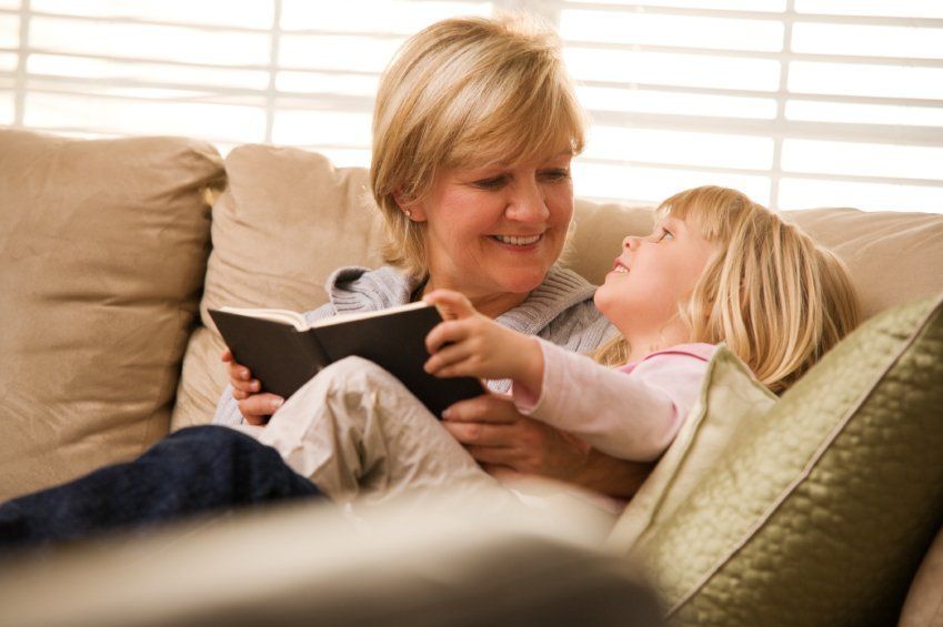 Woman with kid sitting on sofa and reading