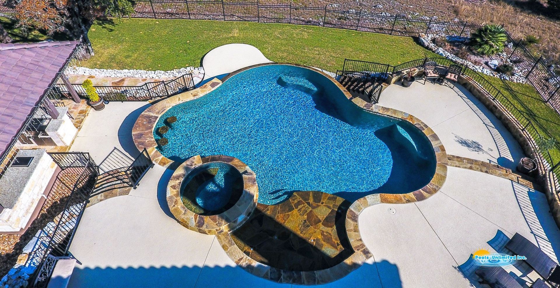 There is a large swimming pool with a hot tub in the middle of it.