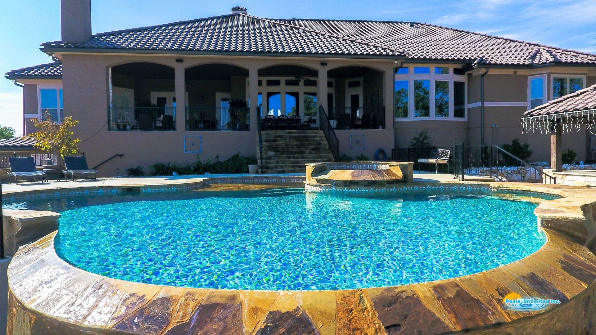 An aerial view of a large swimming pool in the backyard of a house.